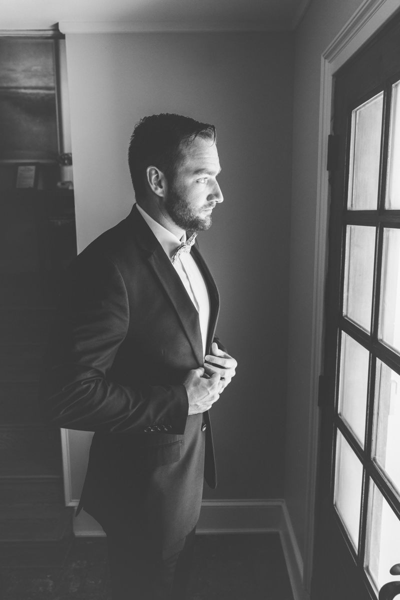 Black-and-white groom portrait buttoning his jacket, candid wedding morning fit check vibes with modern, stylish photography inspo.