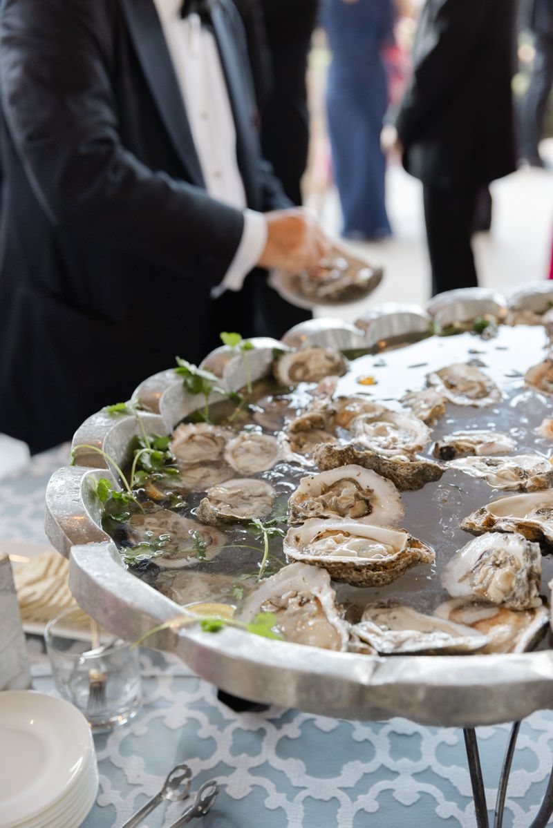 Guest opening fresh oysters at a catered event on St. Simons Island, Georgia. Coastal wedding detail photo.
