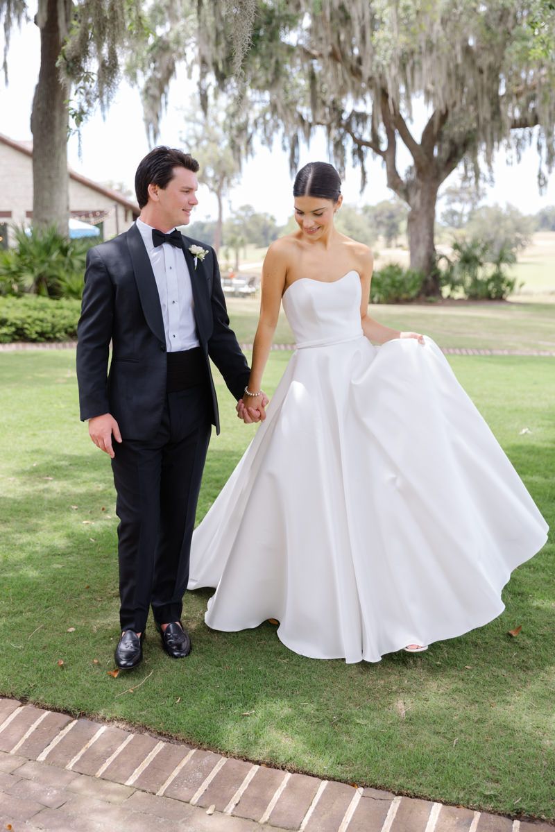 Candid shot of bride and groom walking at Frederica Golf Clubhouse on St. Simons Island, modern wedding photography with chic style.