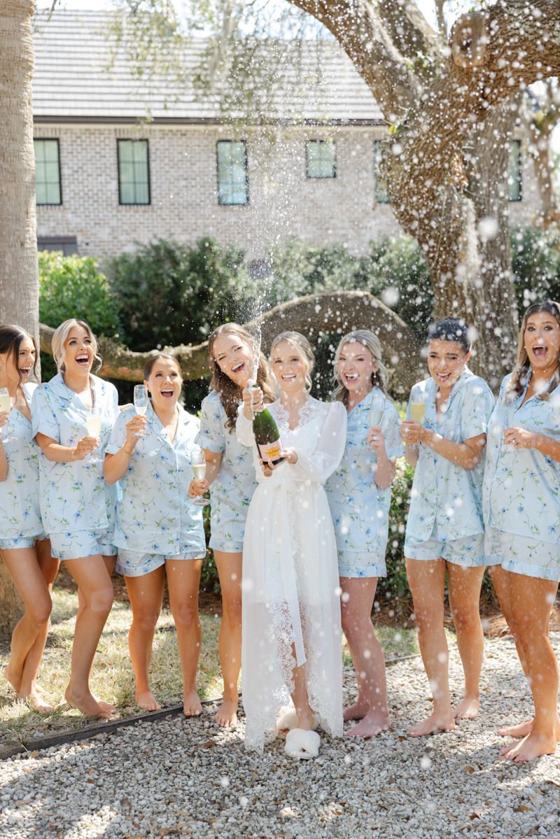 Bride popping champagne with bridesmaids at Sea Island wedding, candid party vibes with fun, trendy photo inspo.