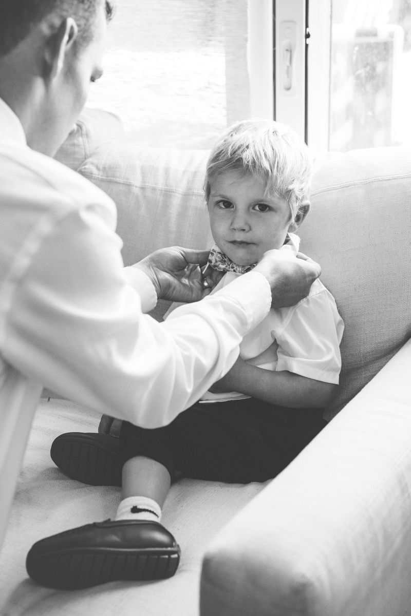 Candid moment of ring bearer getting his shirt buttoned while getting ready for a Sea Island wedding.