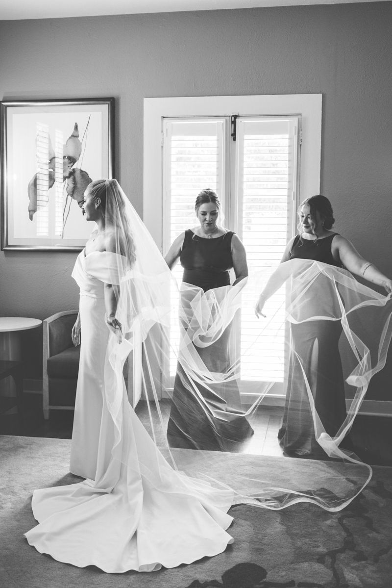 Black-and-white, film-inspired photo of bride getting ready with cathedral-length veil at Jekyll Island Club Resort.