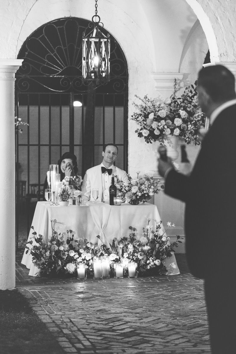Film-inspired wedding reception photo of a toast in the Crane Cottage courtyard on Jekyll Island, captured by wedding photographer.