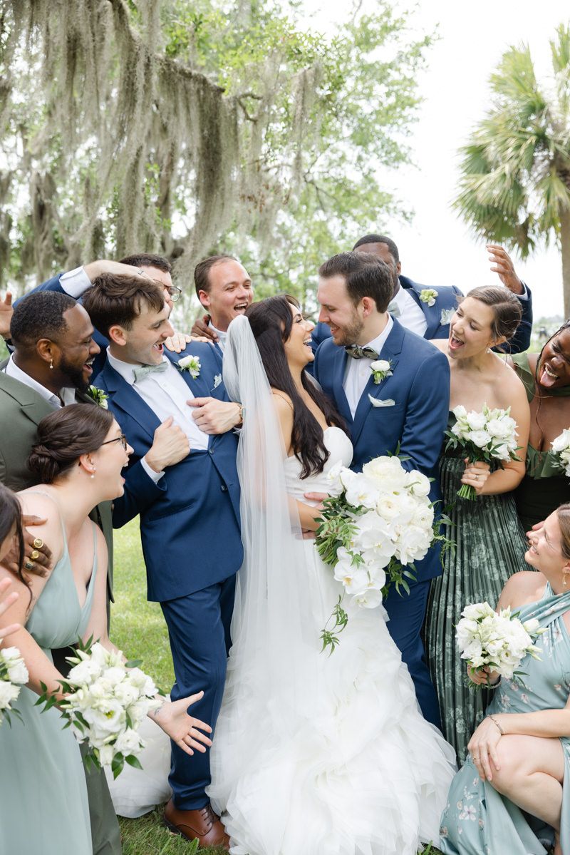 Bride and groom share a fun moment with their wedding party at Captain’s Bluff, St. Simons Island. Modern wedding photography.
