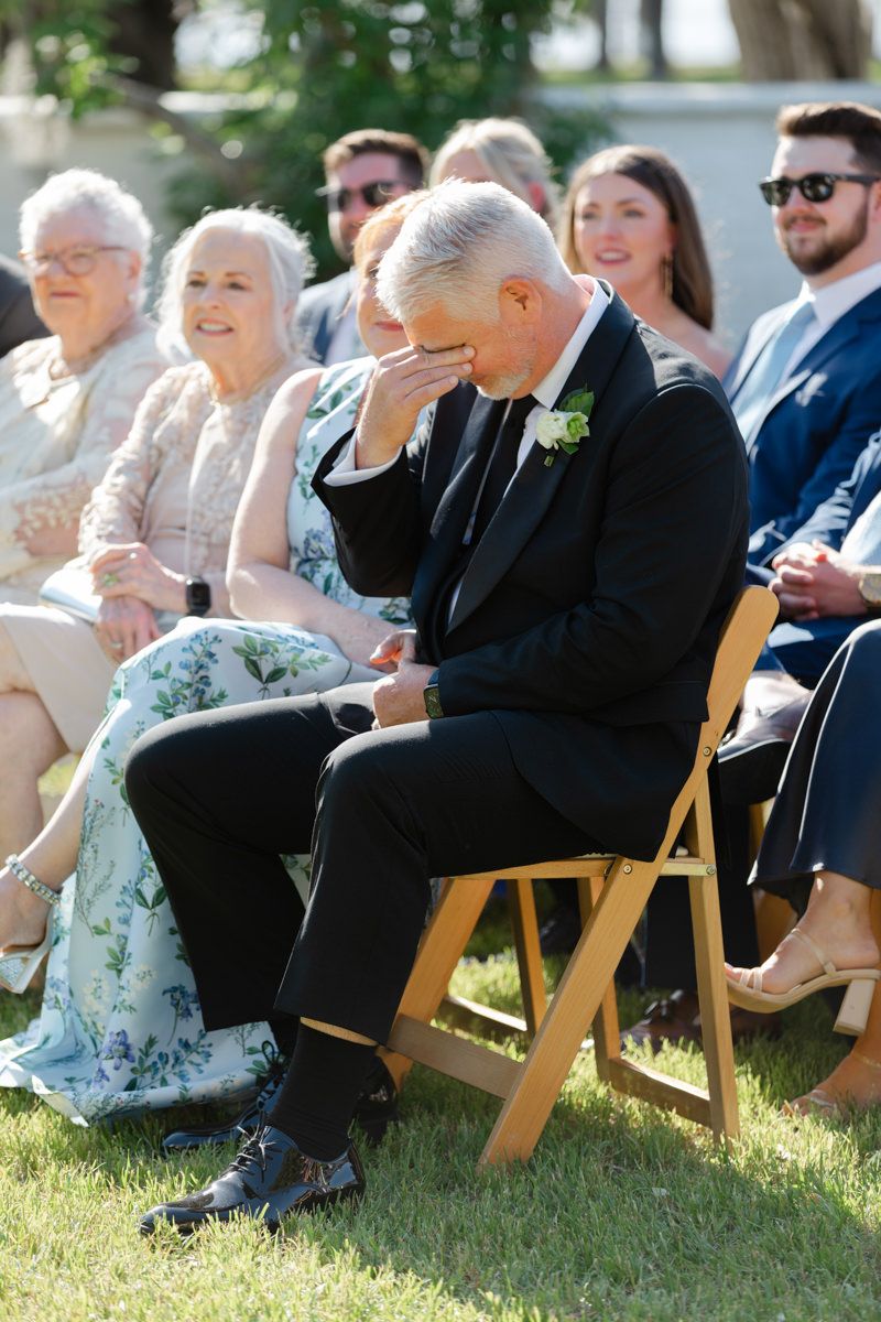 Emotional photo of bride’s dad wiping tears during ceremony at Crane Cottage, Jekyll Island Club Resort, captured by wedding photographer.