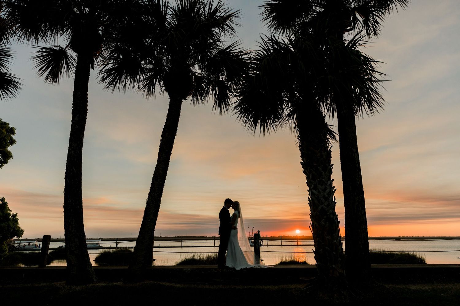 Romantic sunset portrait of bride and groom on Riverfront Lawn, Crane Cottage, Jekyll Island, Georgia by fine art wedding photographer.