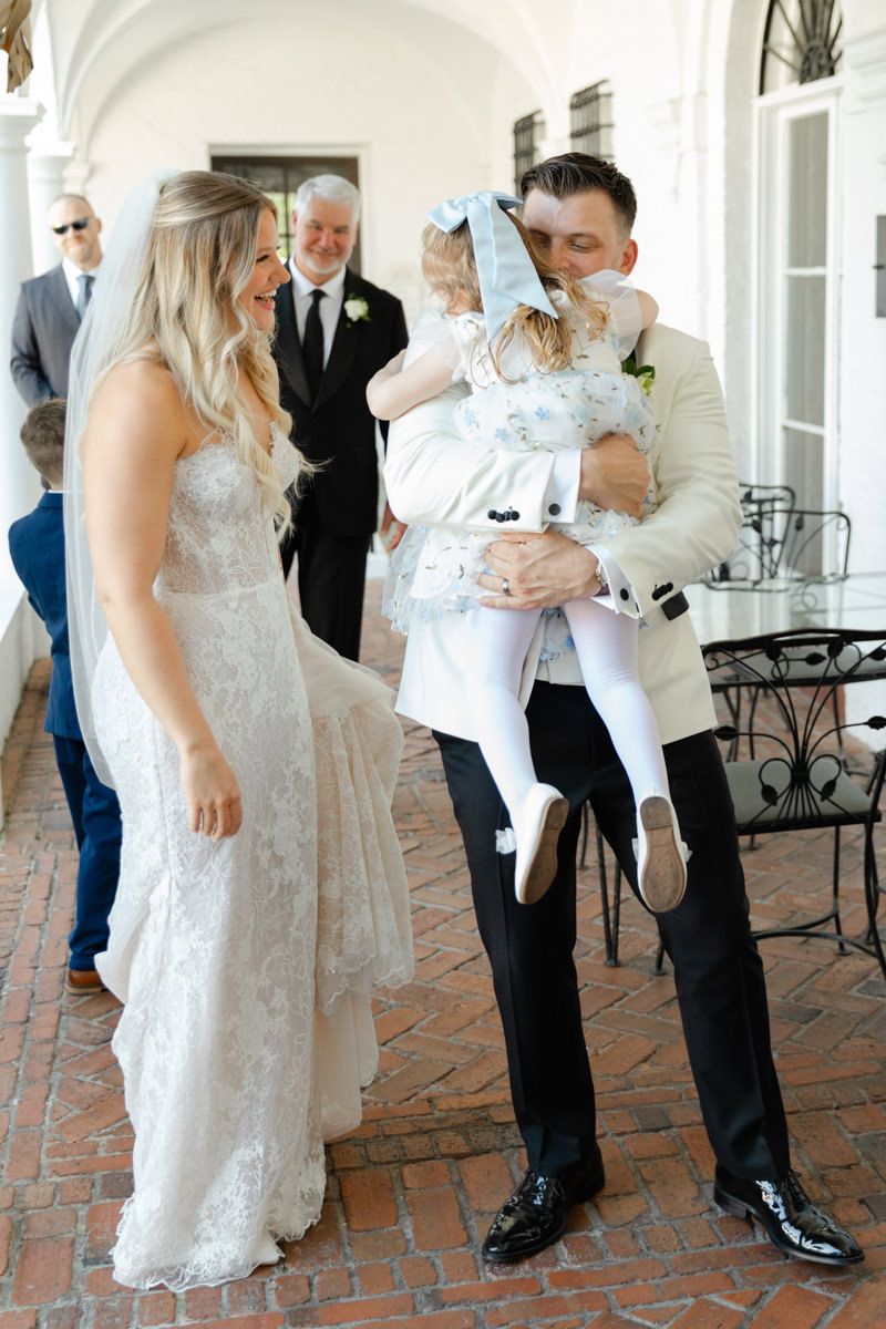 Sweet candid of groom hugging flower girl at Jekyll Island Club wedding, modern photography with heartwarming vibes.
