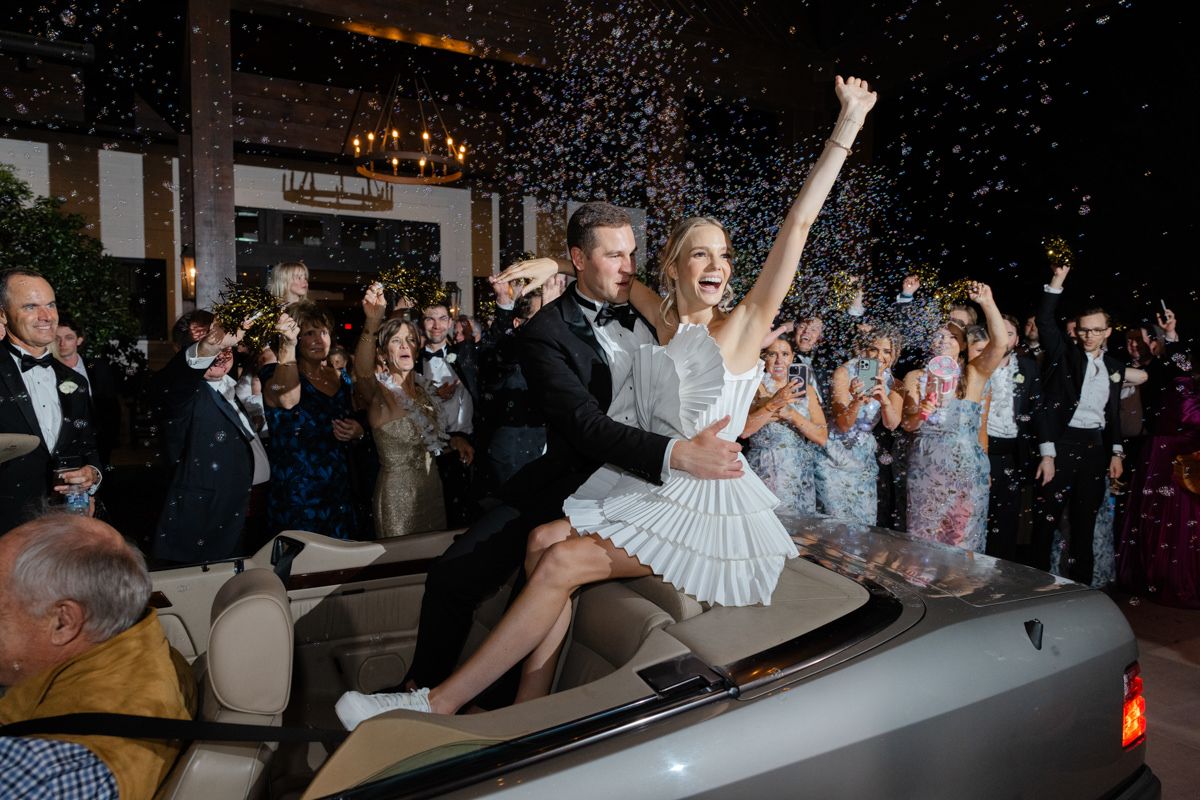 Bride and groom’s grand exit with bubbles and waving guests at Forbes Farm on St. Simons Island, driving off in a getaway car.