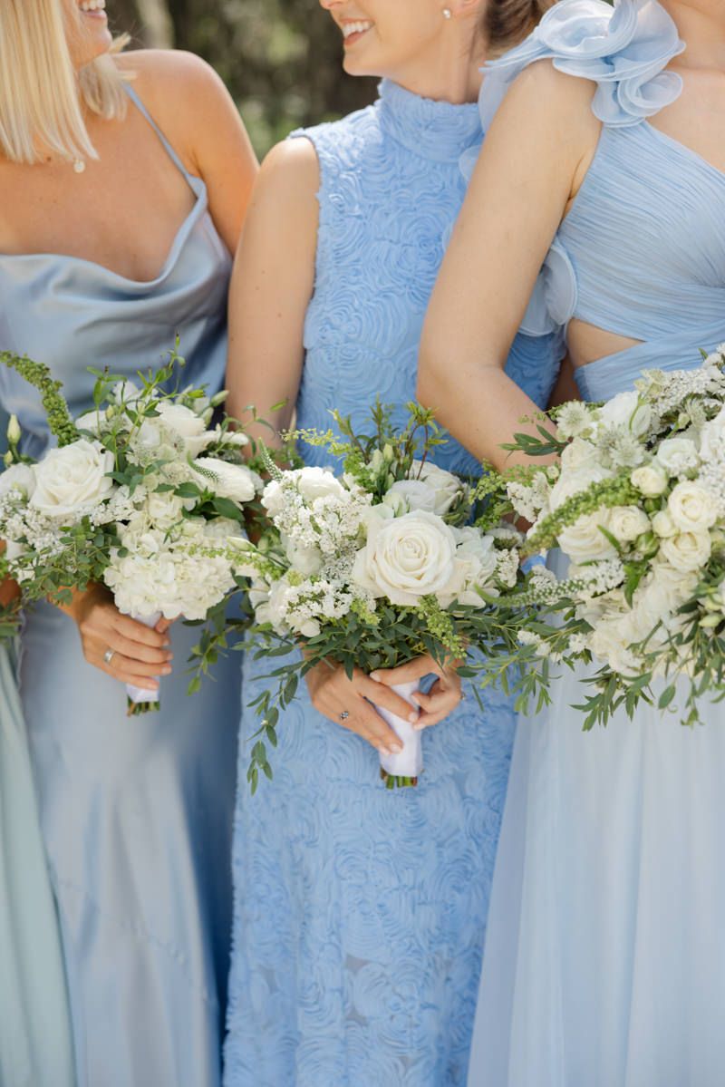 Bridesmaids in blue dresses holding floral bouquets at Forbes Farm, St. Simons Island wedding photography with elegant style.