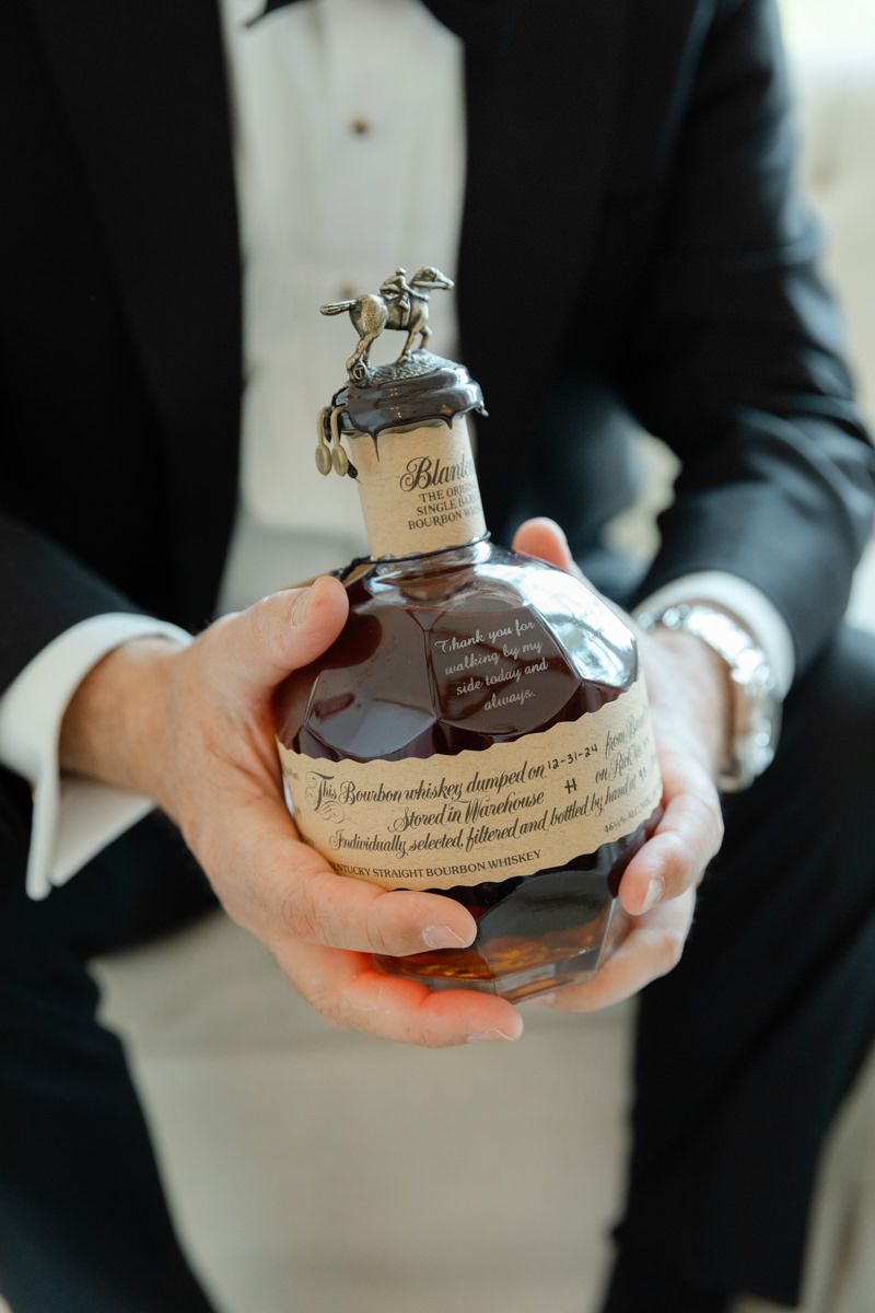 Groom’s gift of bourbon, a Southern wedding tradition. Captured at Sea Island by documentary-style wedding photographers.
