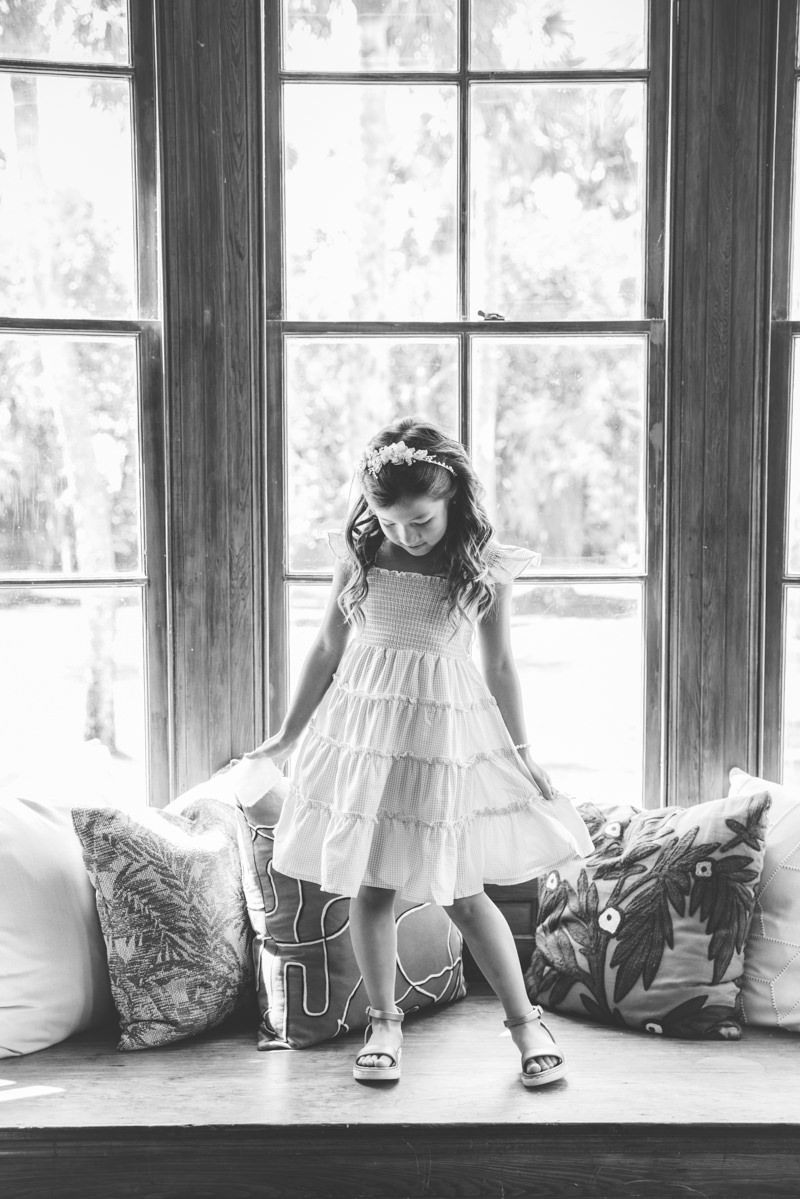 Flower girl playing by the window at Cherokee Cottage, Jekyll Island Club wedding captured by photographer.
