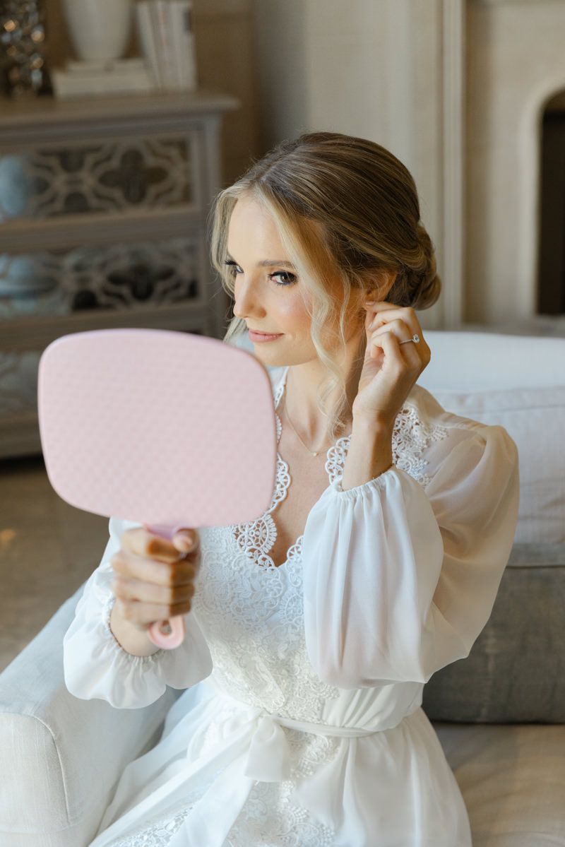 Bride checking makeup in mirror before Sea Island wedding ceremony, chic candid bridal prep photo inspo.