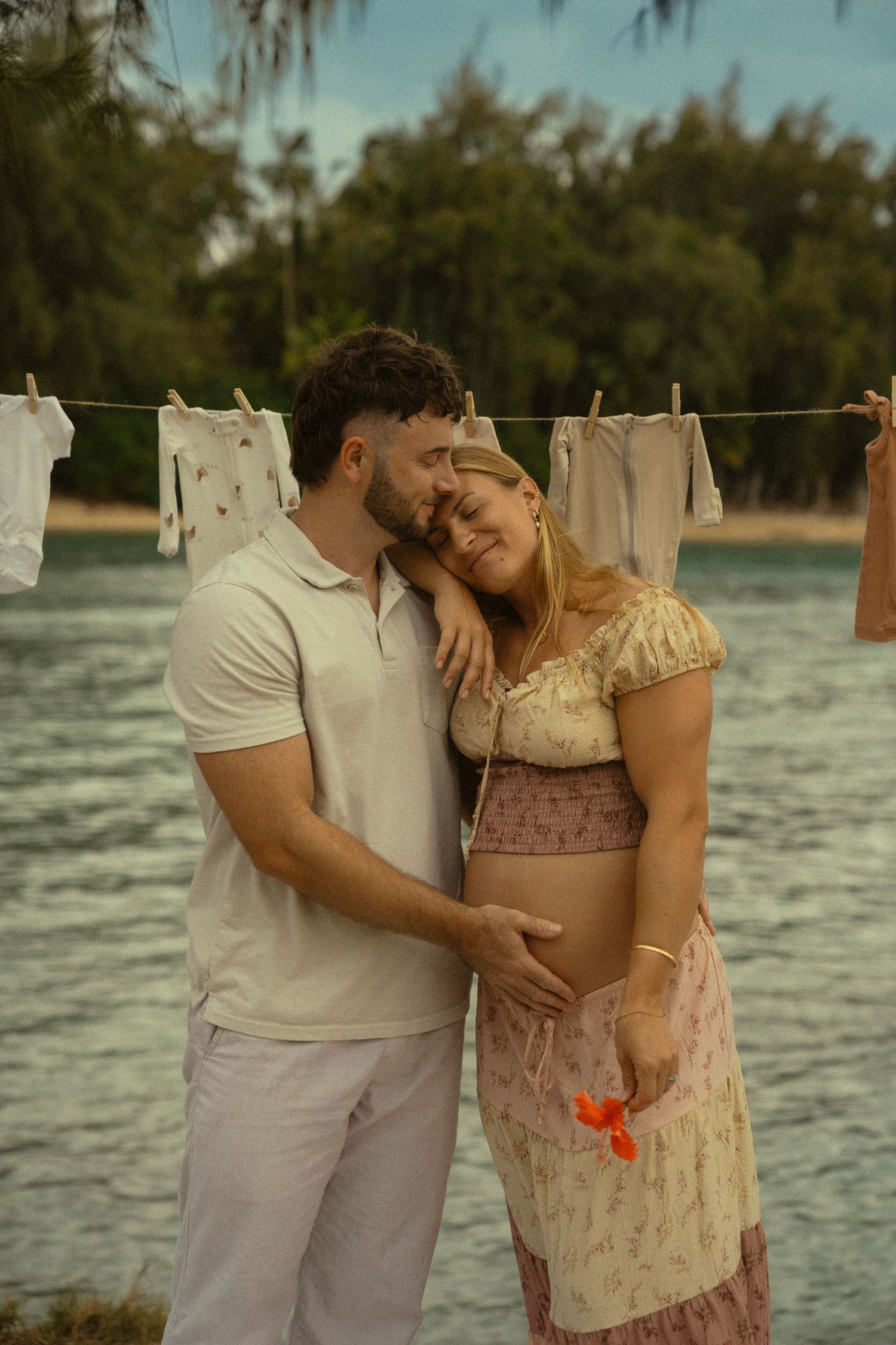 A romantic moment captured on a beach with vintage clothes hanging in the background.