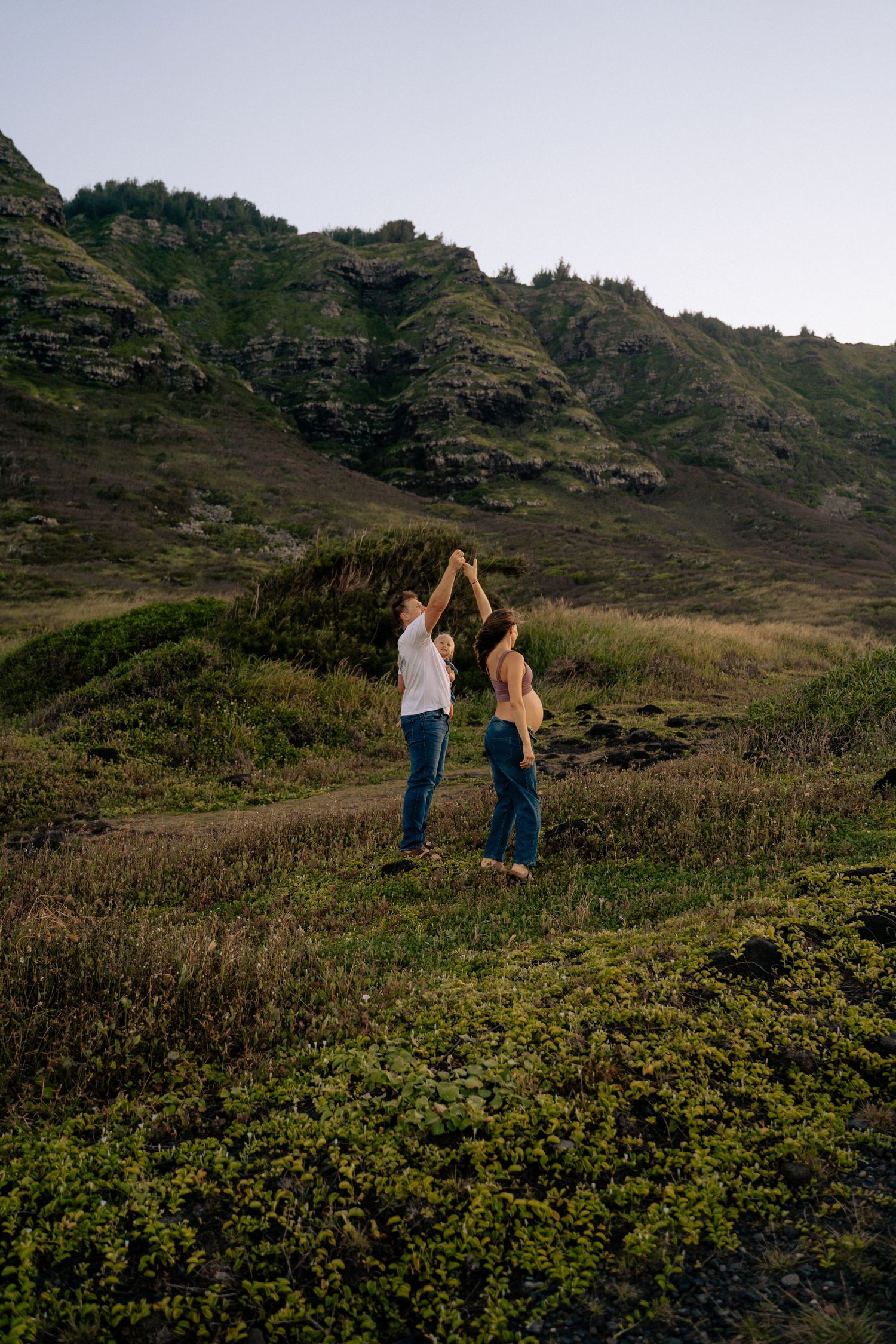 Couple walking hand in hand through mountain terrain with dramatic landscape views.