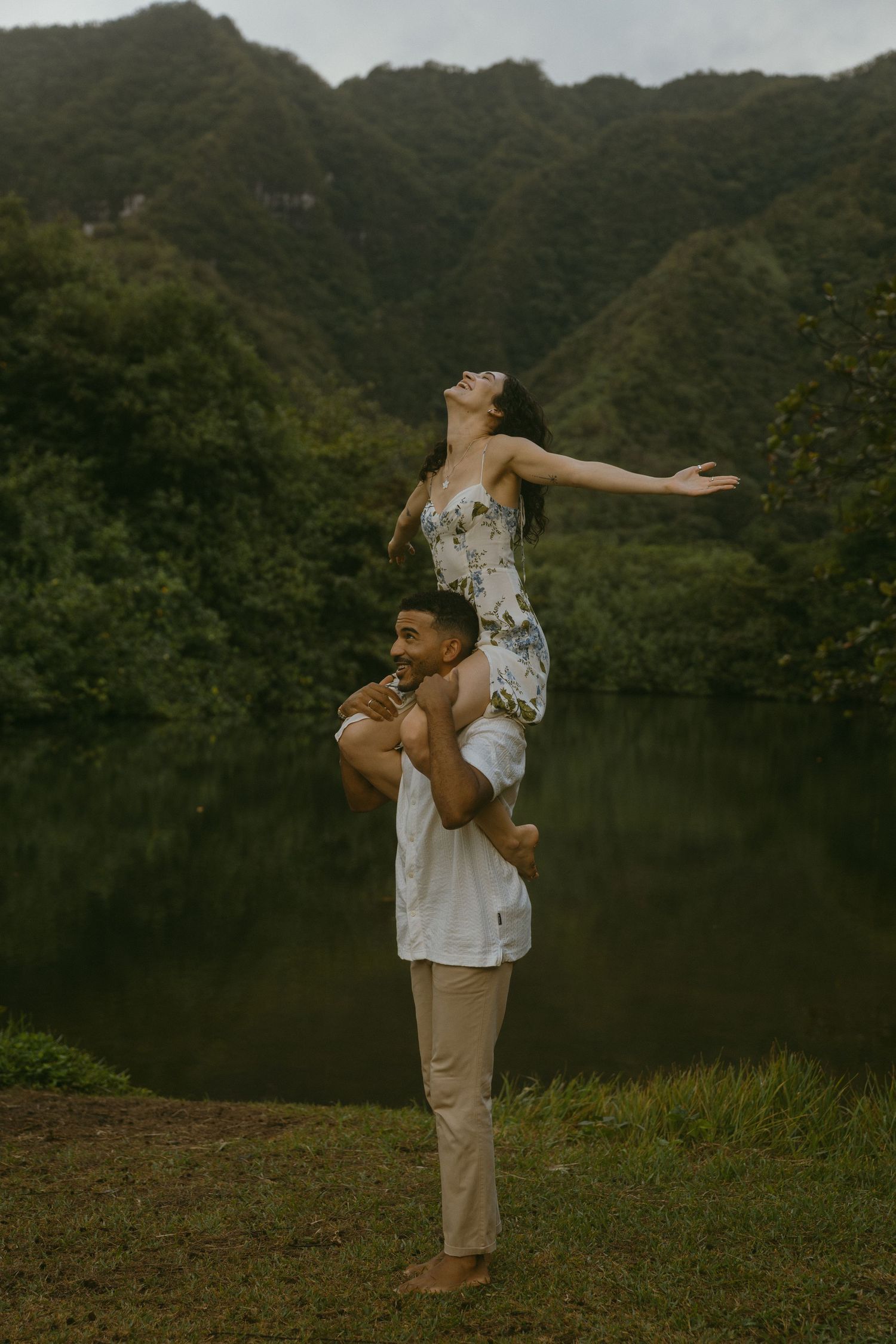 A couple performing fun lifts and poses during their engagement photoshoot by a scenic mountain lake.