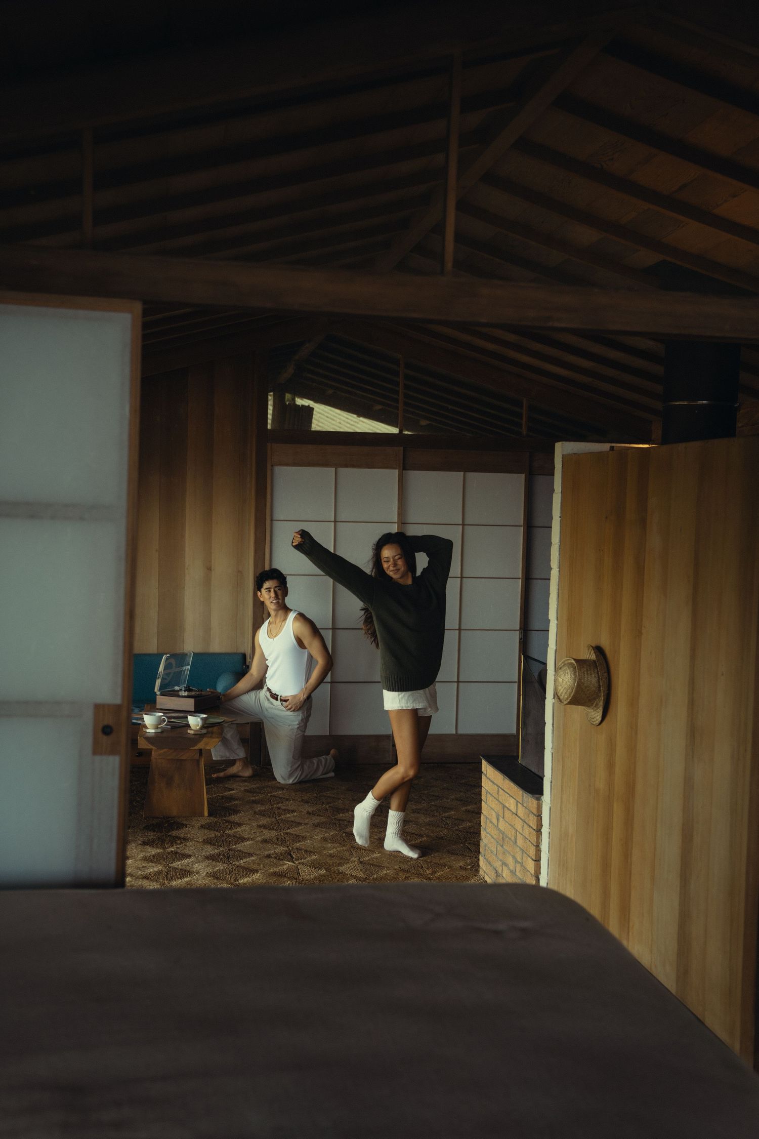 Person stretching in dance pose inside minimalist Japanese-style room.