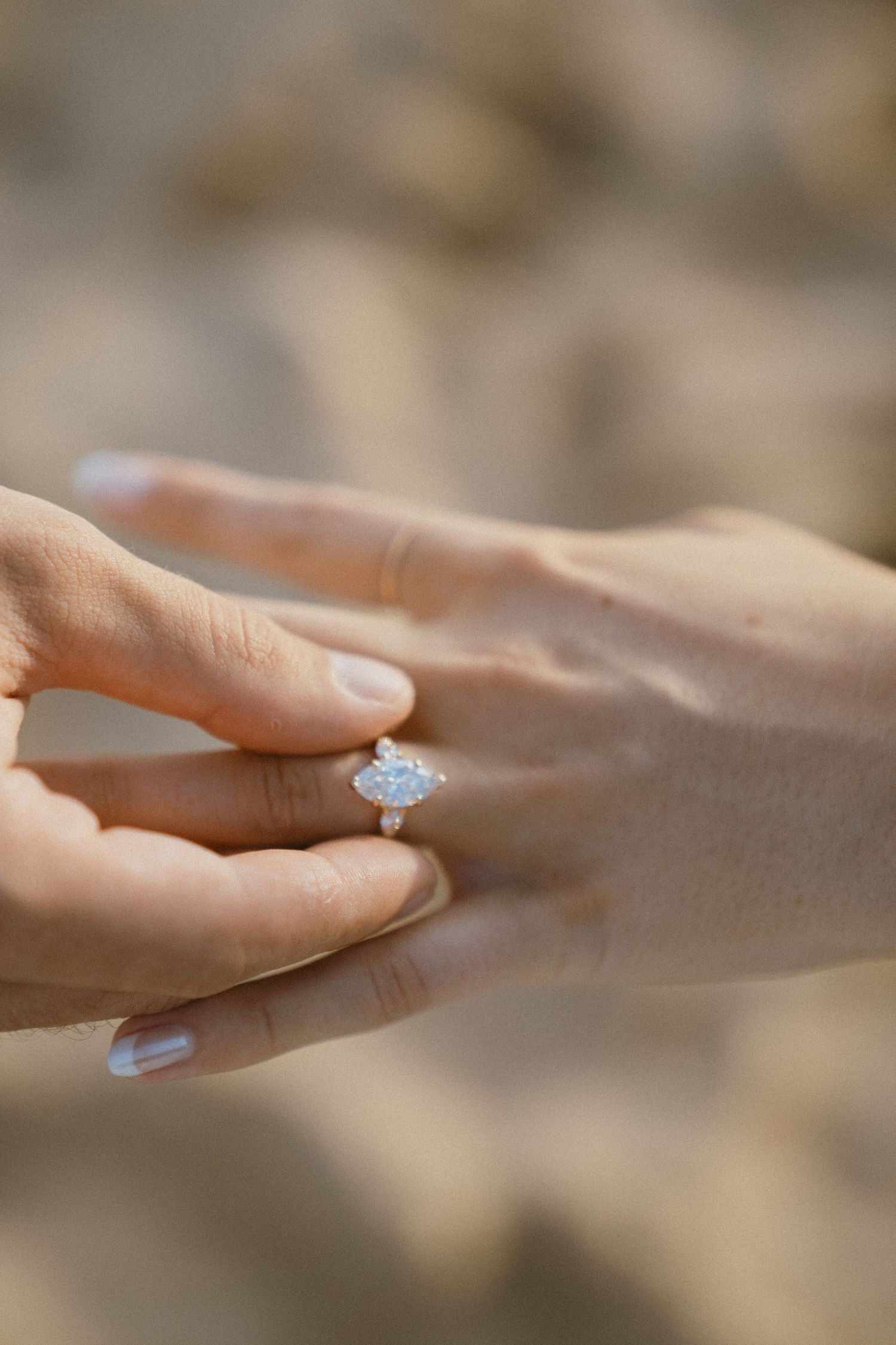 Close-up of hands displaying an elegant engagement ring with a blue stone.