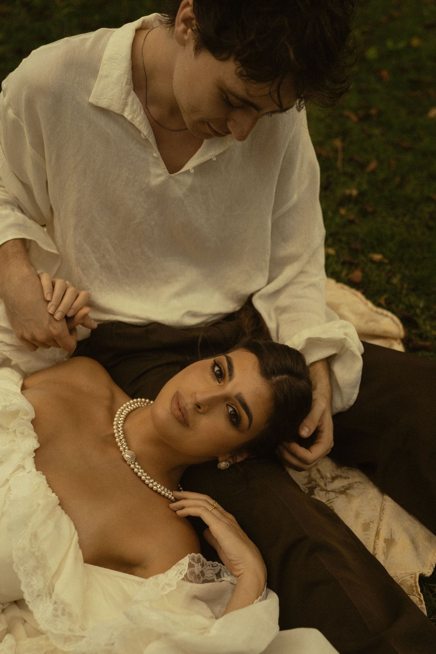 A tender moment captured between two people in white clothing against a natural backdrop.