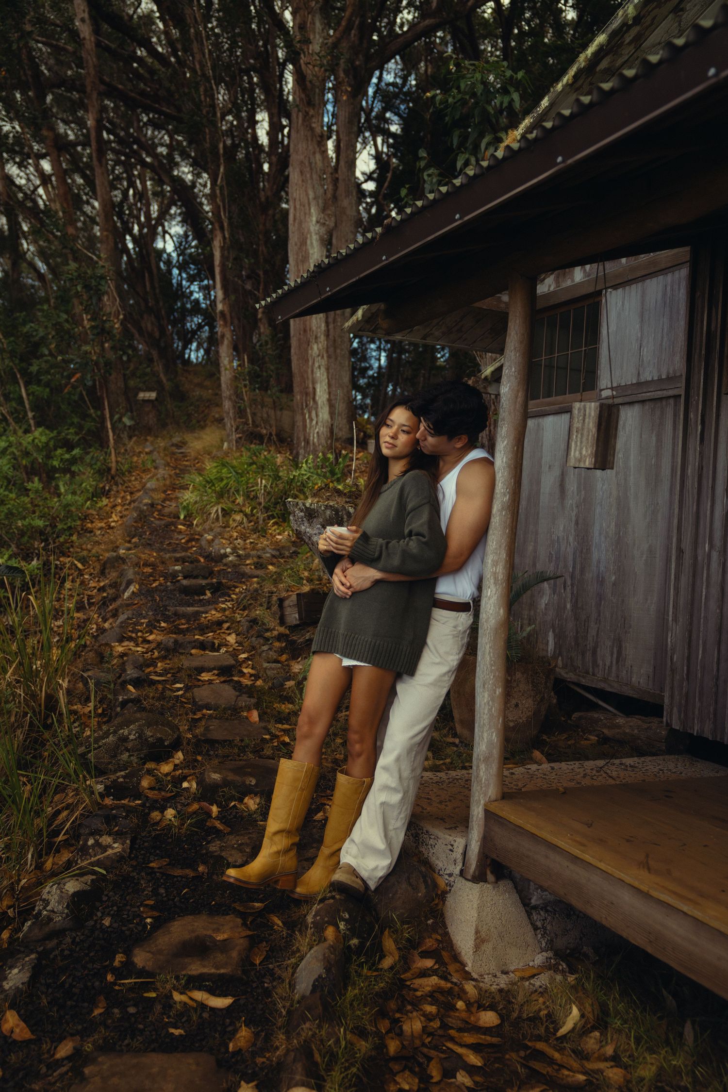 A rustic wooden cabin nestled among tall trees creates a cozy forest setting.