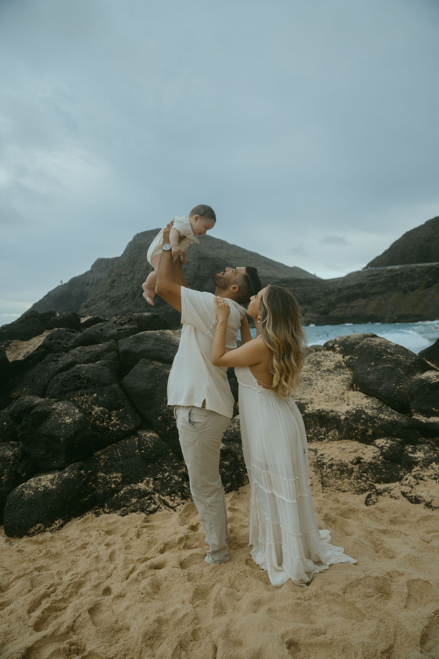 Joyful family photography session against dramatic coastal landscape and cloudy sky.