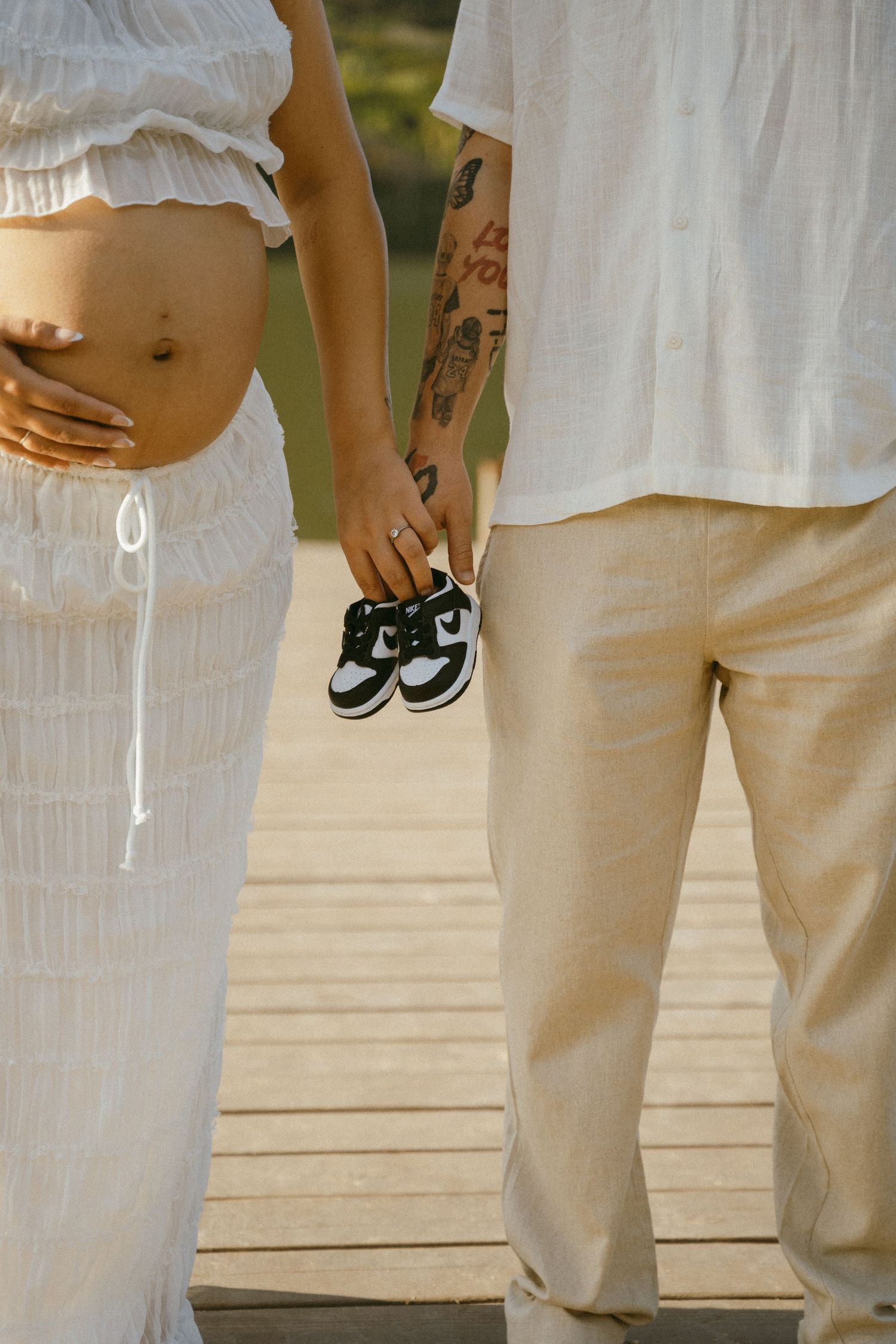 A maternity photoshoot showing close-up details of a couple in white clothing.