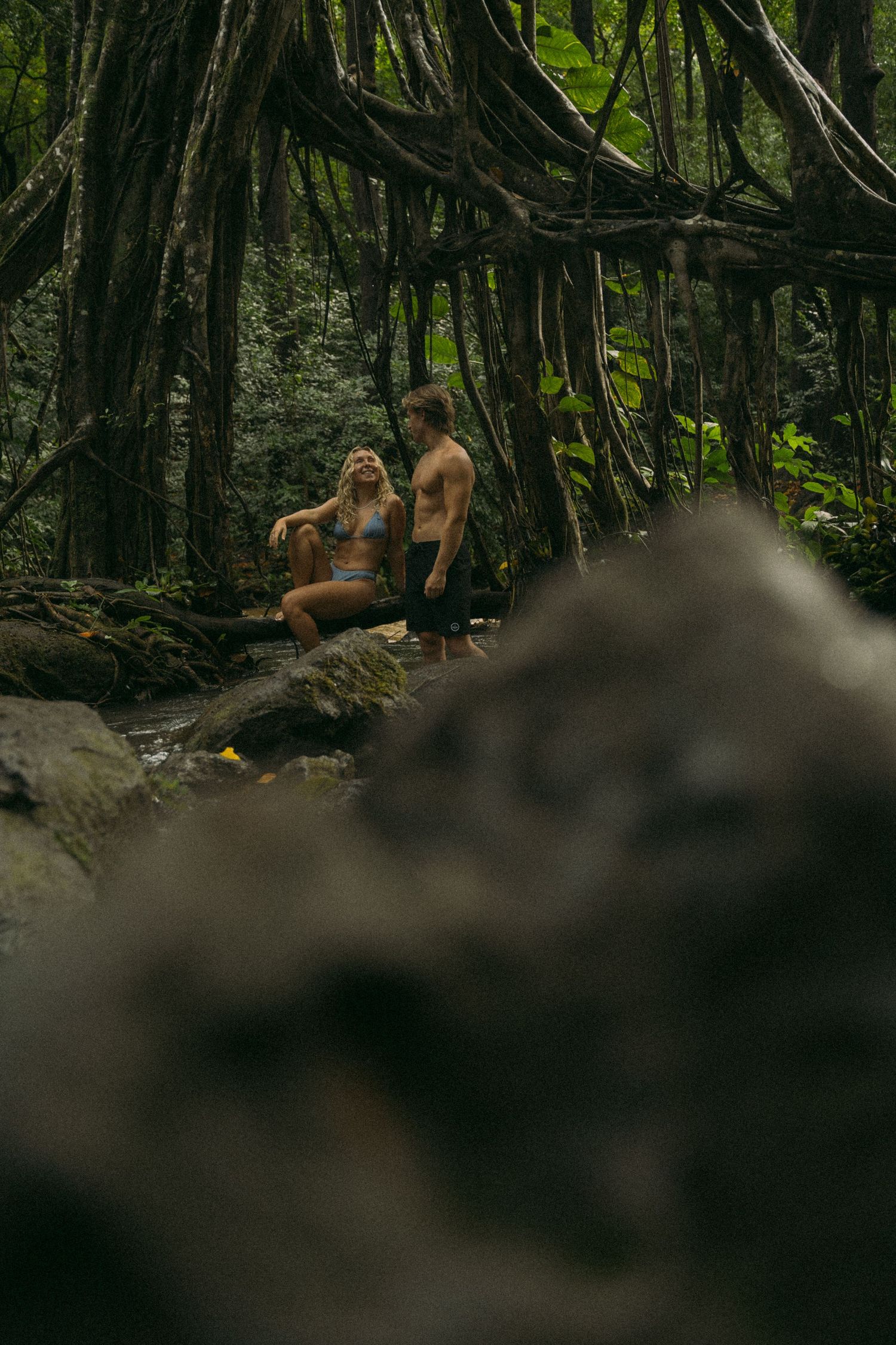 Two people enjoy a secluded moment in a lush tropical forest setting.