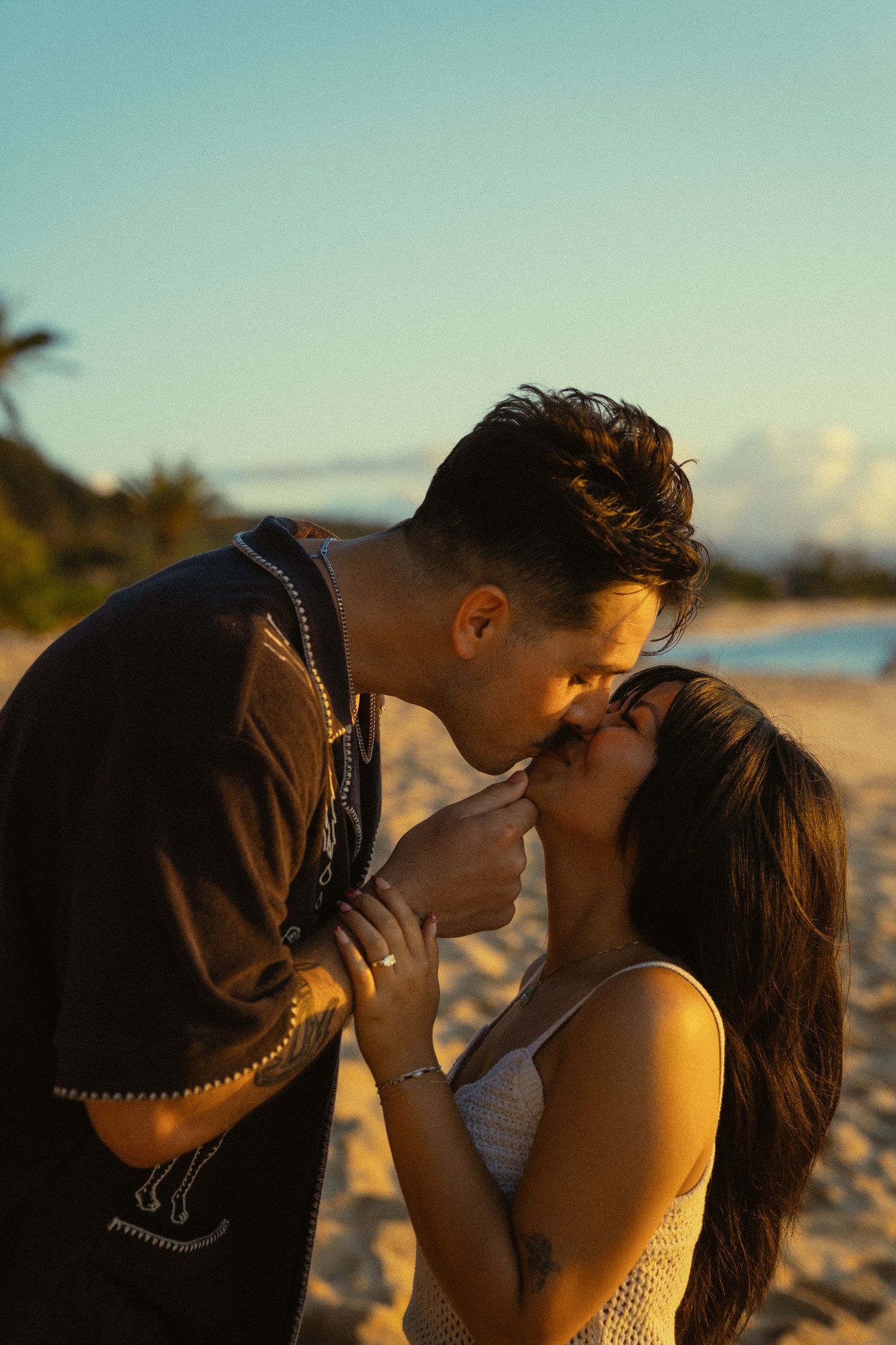 A tender beach photoshoot silhouetted against the golden sunset sky.