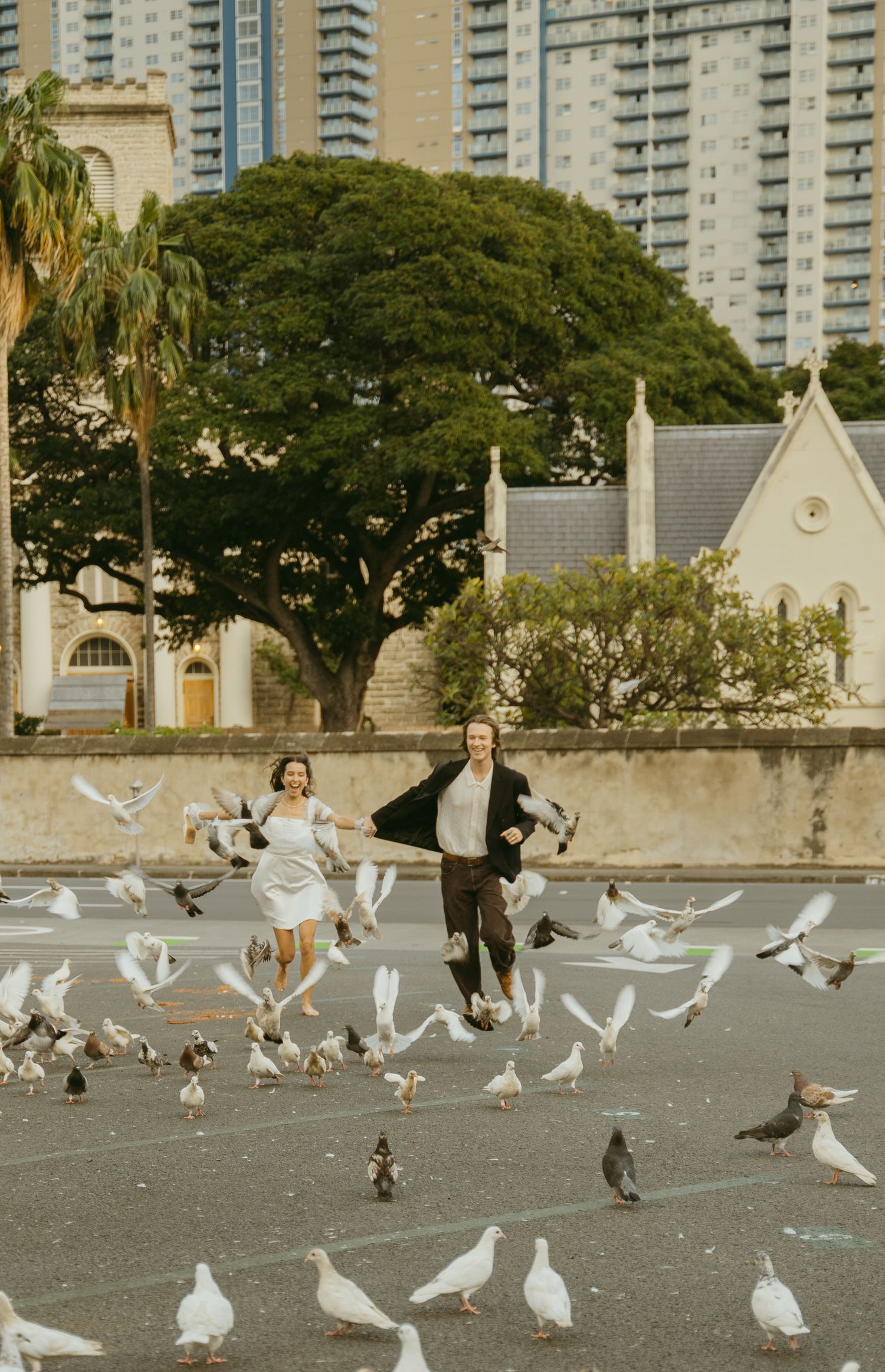Wedding couple running through a flock of white doves in an urban setting.