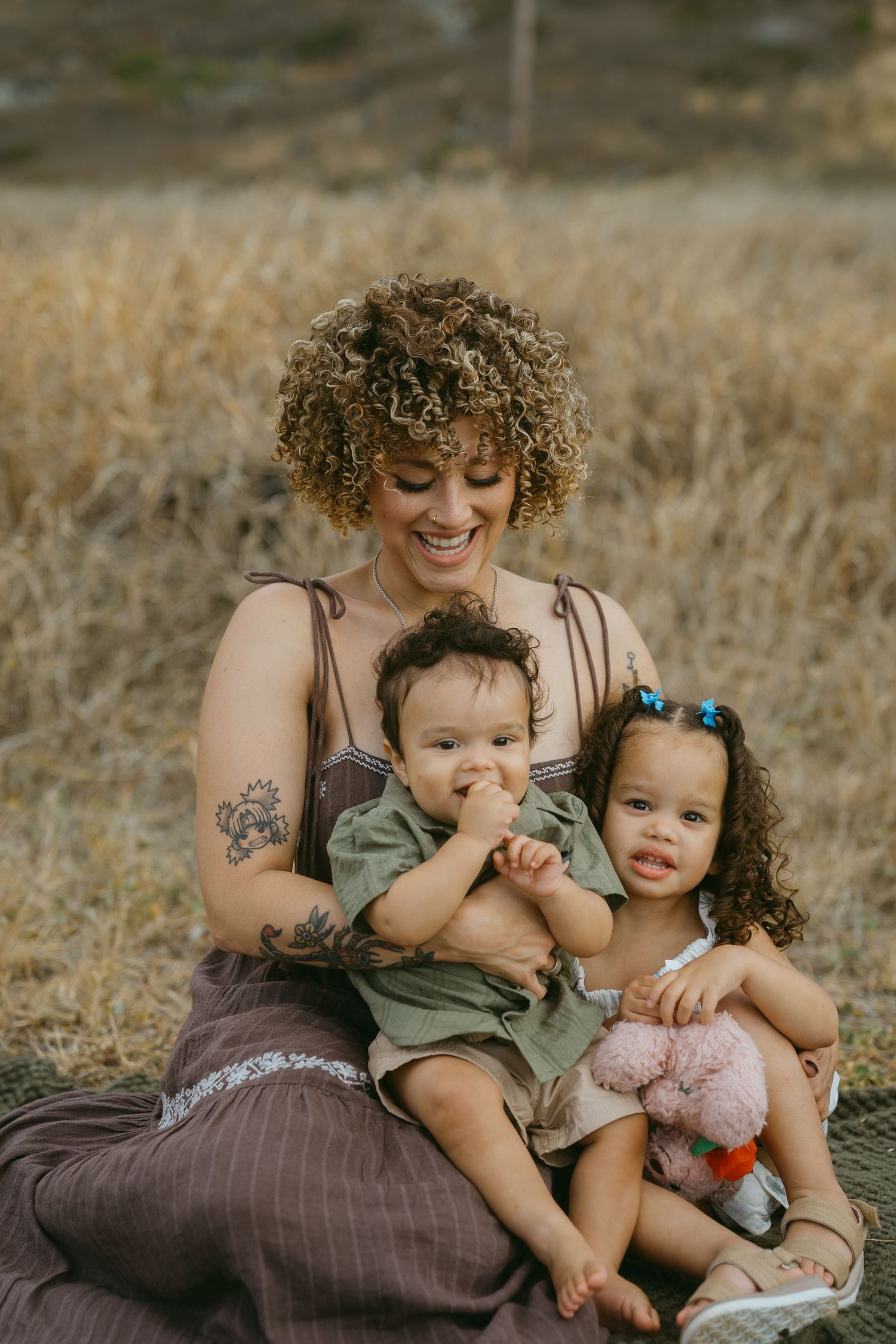 Joyful family cuddles and laughs together during outdoor photo session.