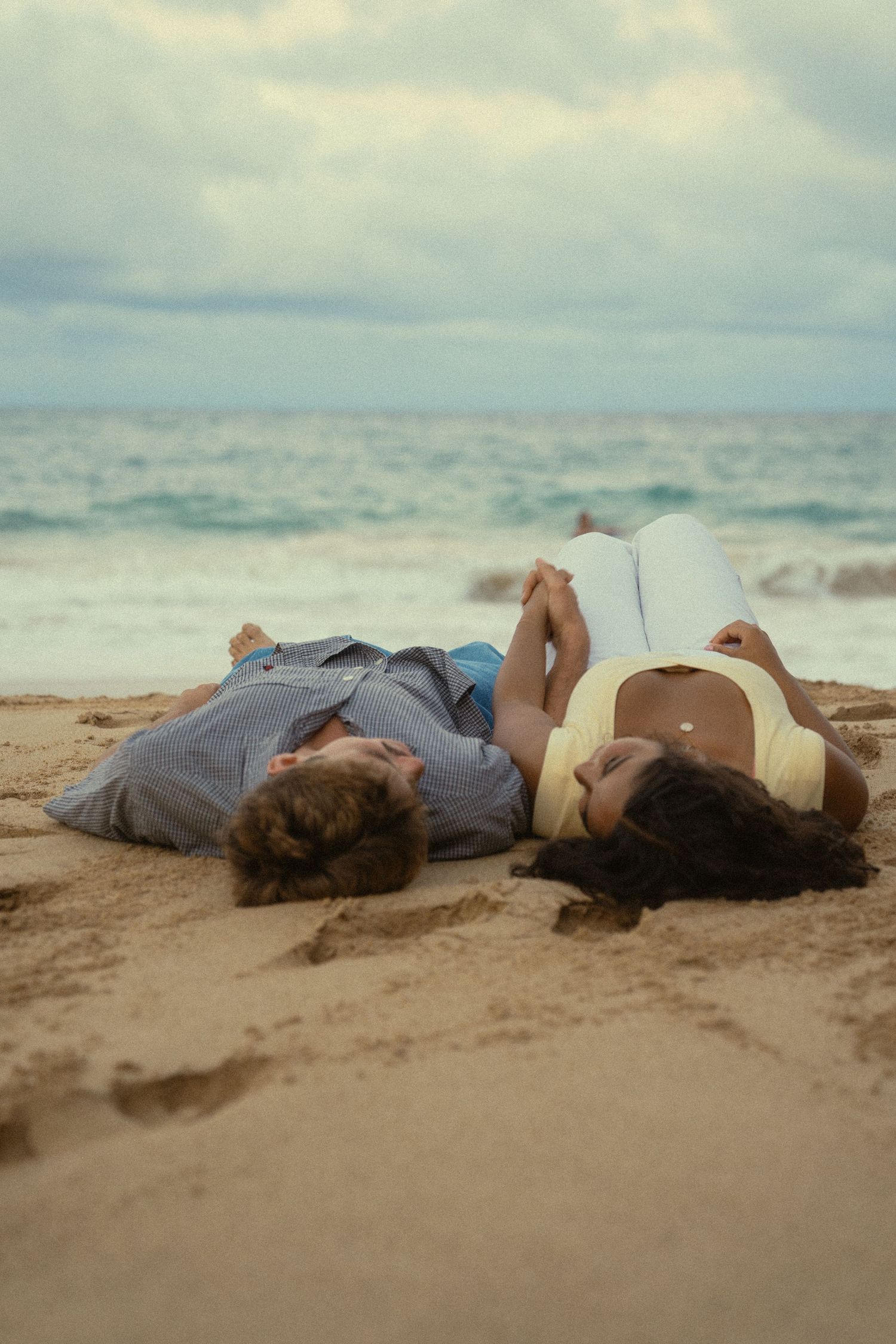 A couple lies peacefully on the sandy beach at sunset.