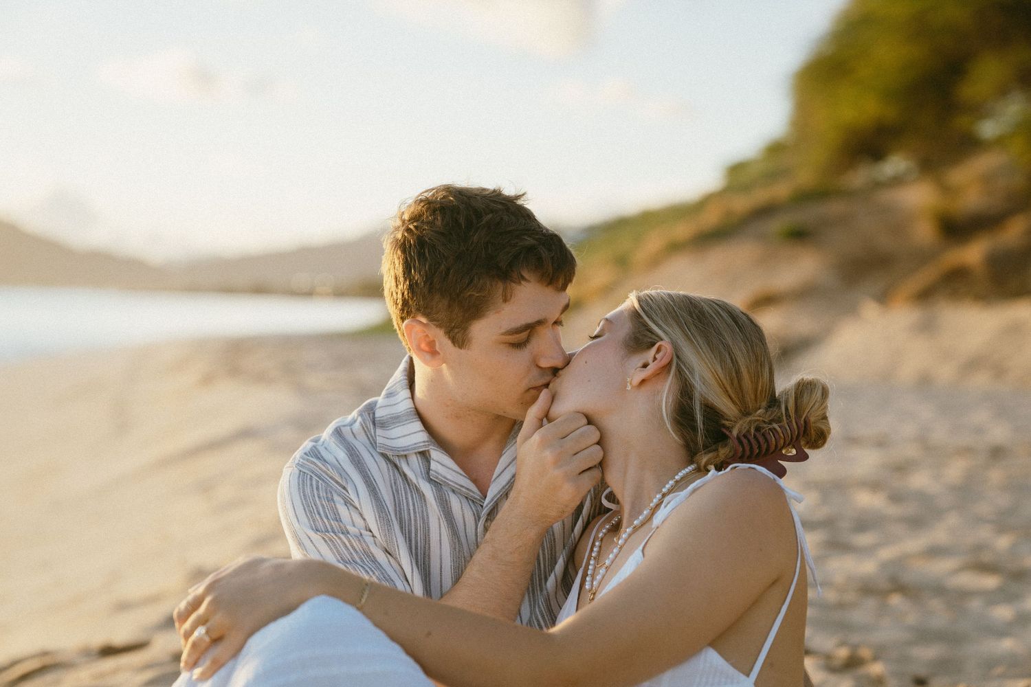 A tender romantic moment shared between a couple on a sunlit beach.