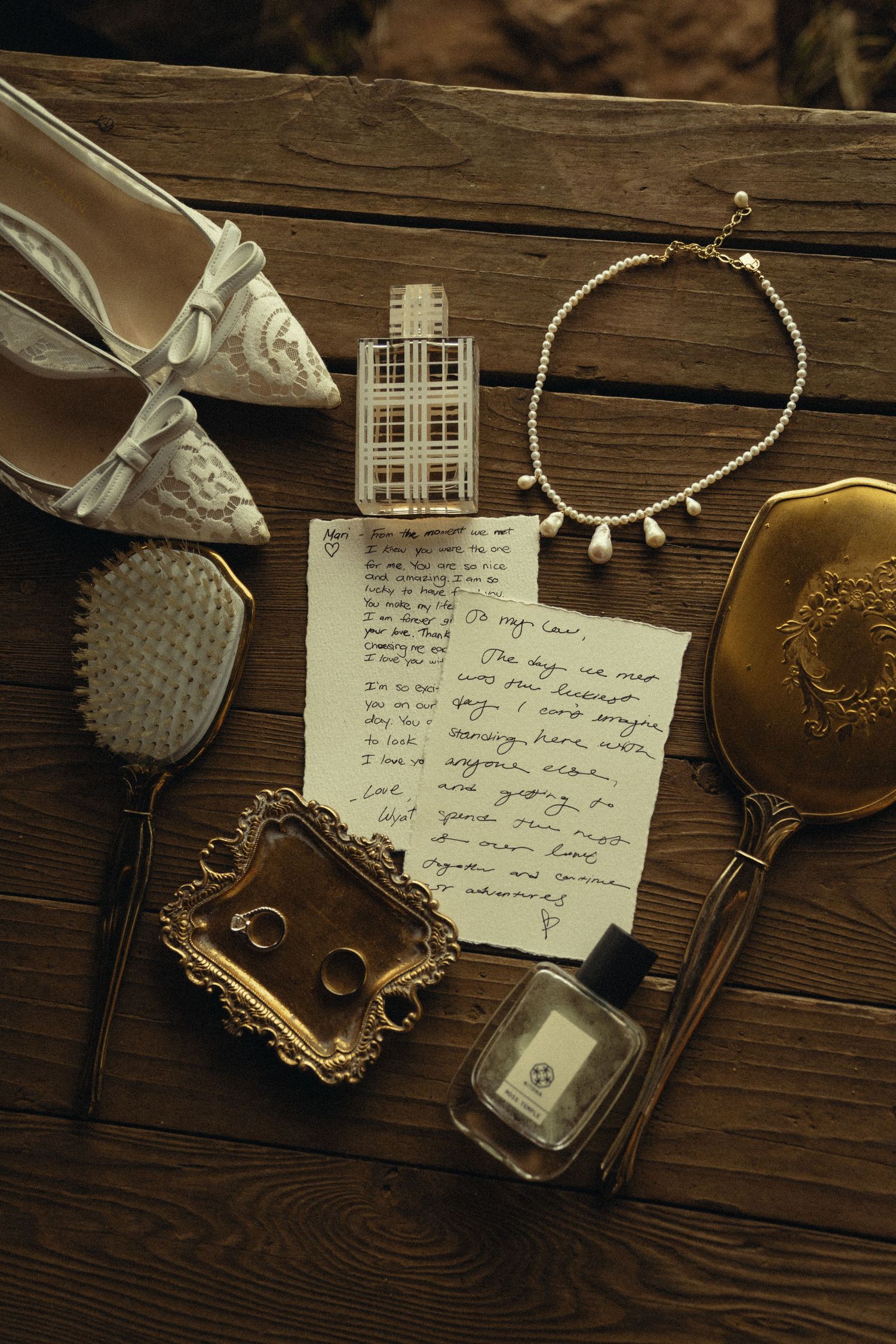 Vintage items including handwritten letters, jewelry, and antique frames arranged on dark wooden surface.