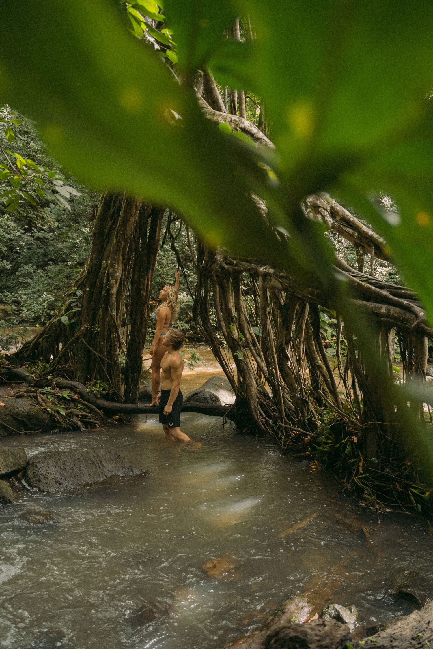 People exploring a scenic river surrounded by twisted tree roots and rocks.