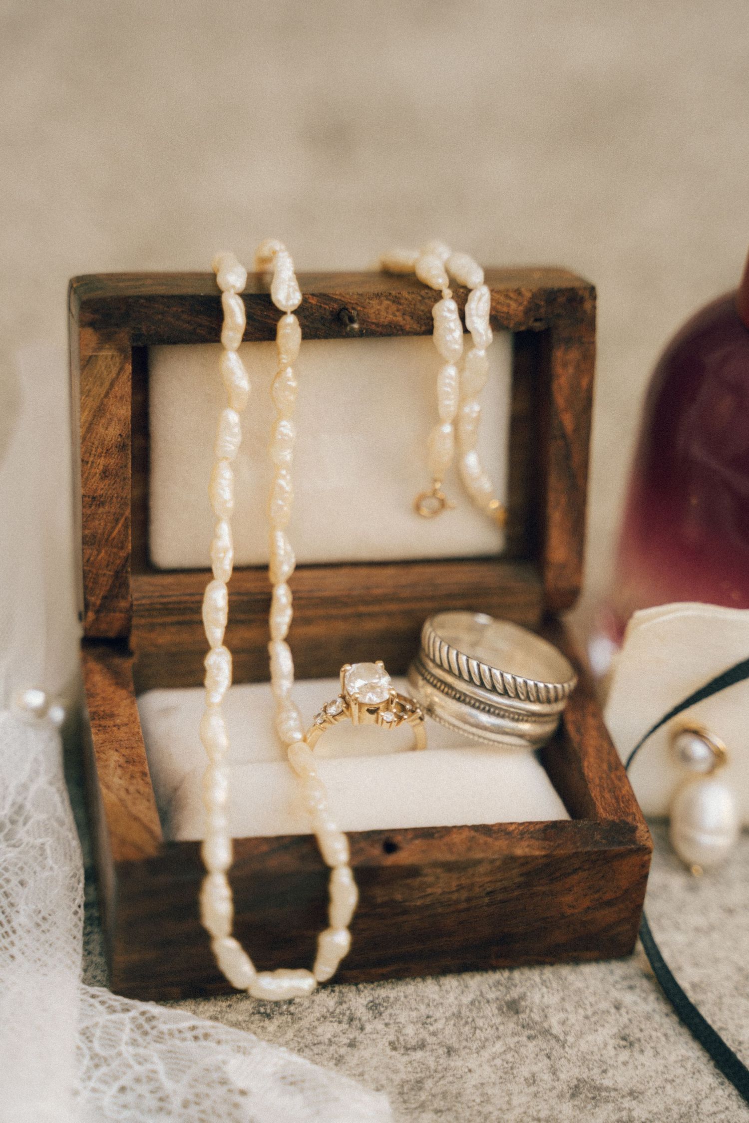 Pearl necklace and wedding accessories displayed on a rustic wooden box.