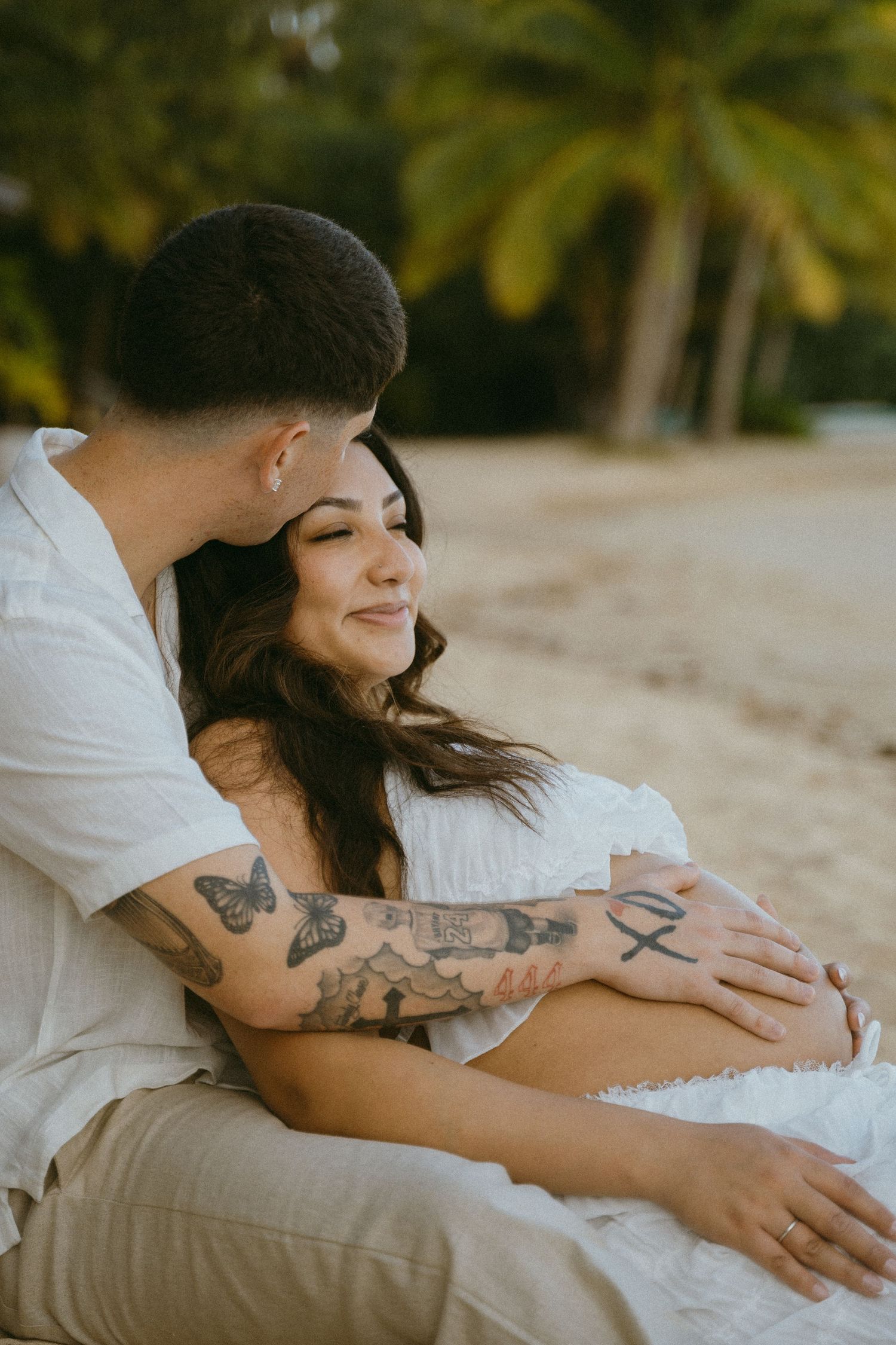An intimate maternity photo showing a couple embracing on a beach.