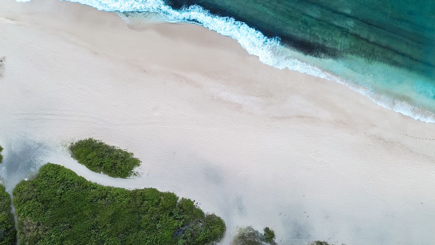 Aerial view of pristine coastline with white sandy beach meeting turquoise waters.