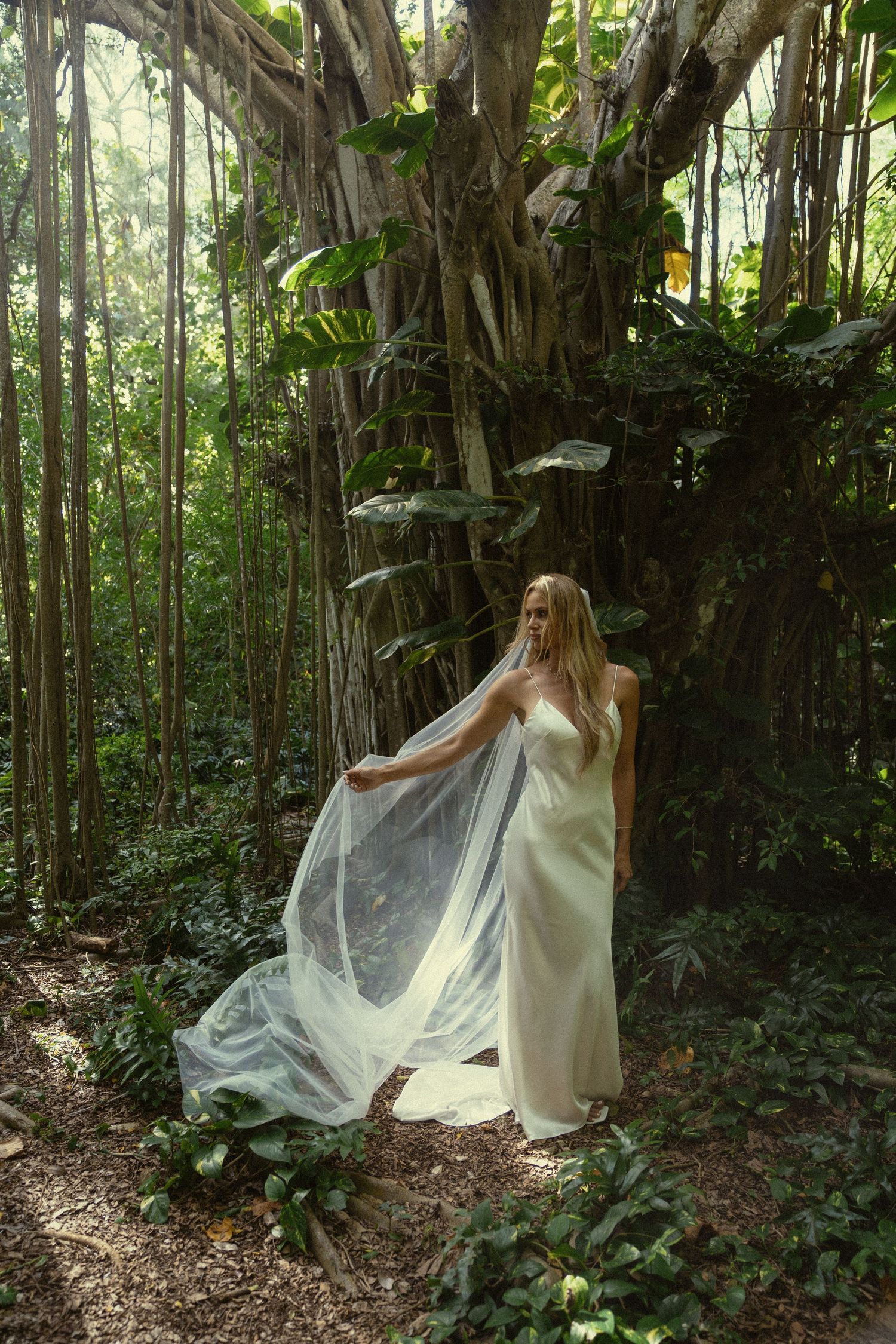 A flowing white dress catches the breeze in a mystical bamboo forest setting.