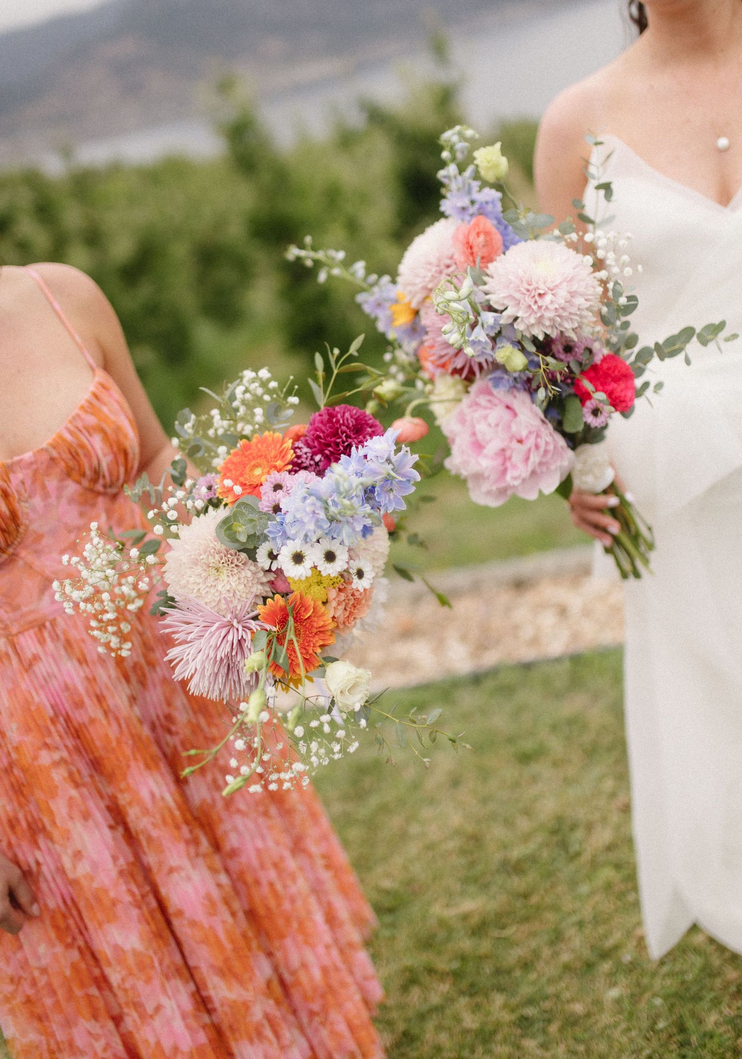 Colorful wildflower wedding bouquets with pink peonies, baby's breath, and mixed blooms against an outdoor setting.