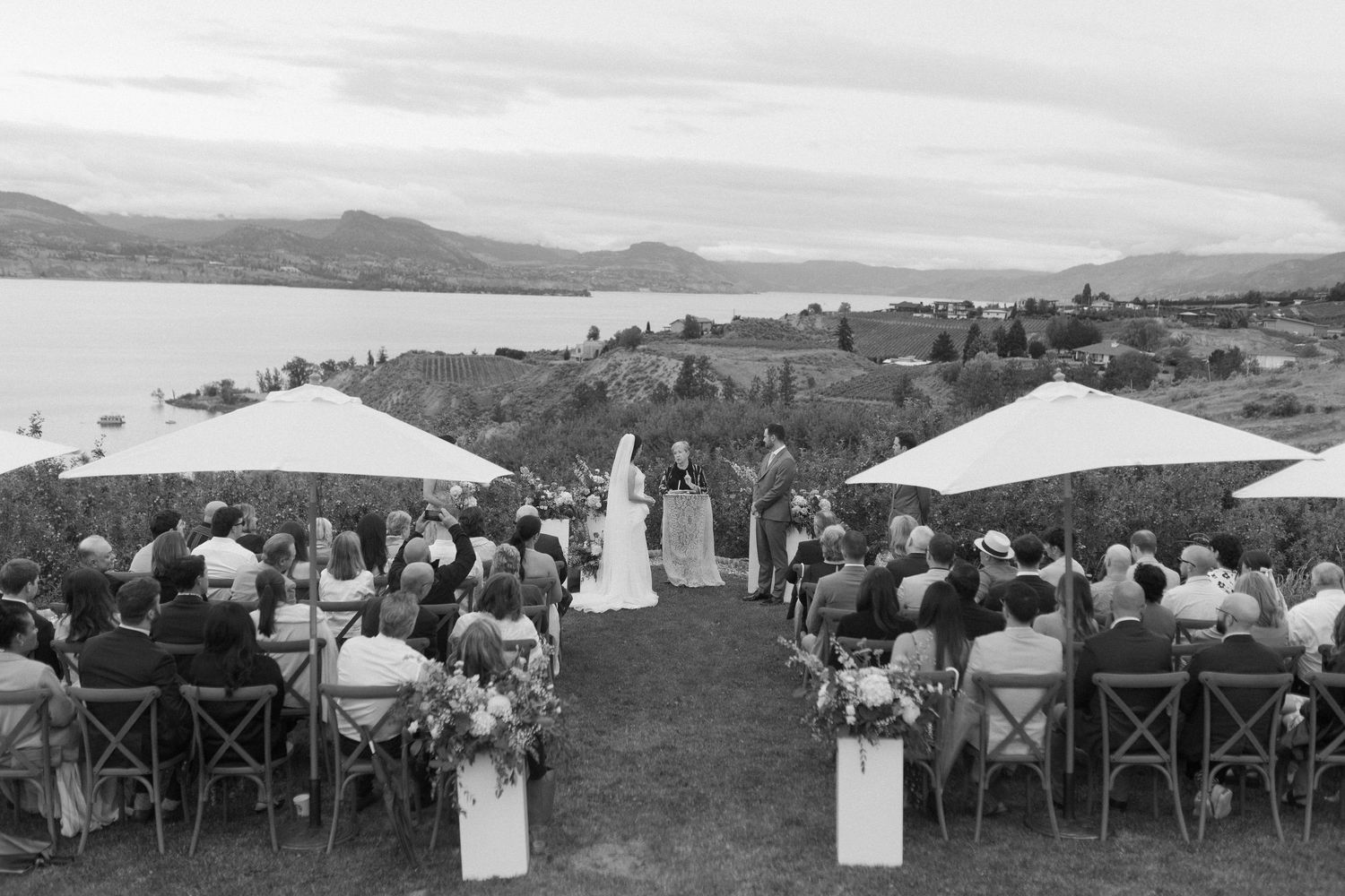 Panoramic view of an outdoor wedding reception with white tents and mountain scenery.