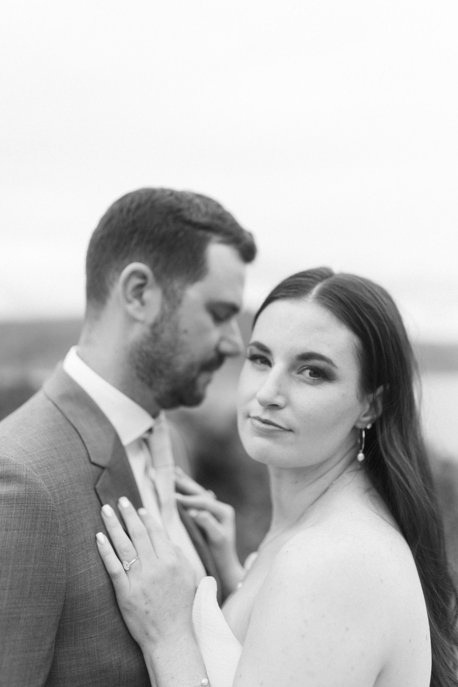 A romantic black and white portrait of a couple sharing an intimate moment outdoors.