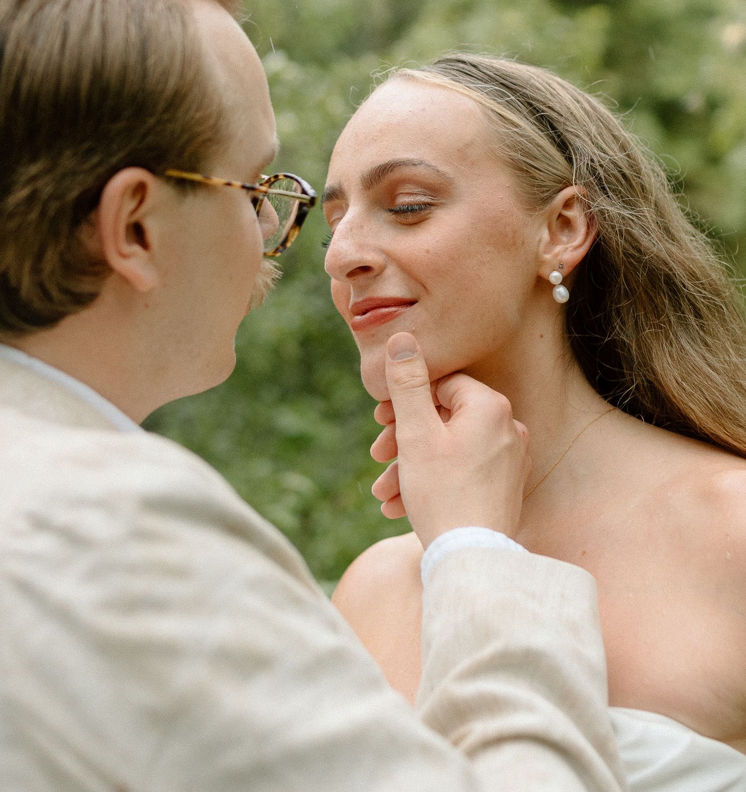 A tender romantic moment between two people during what appears to be an outdoor wedding photoshoot.