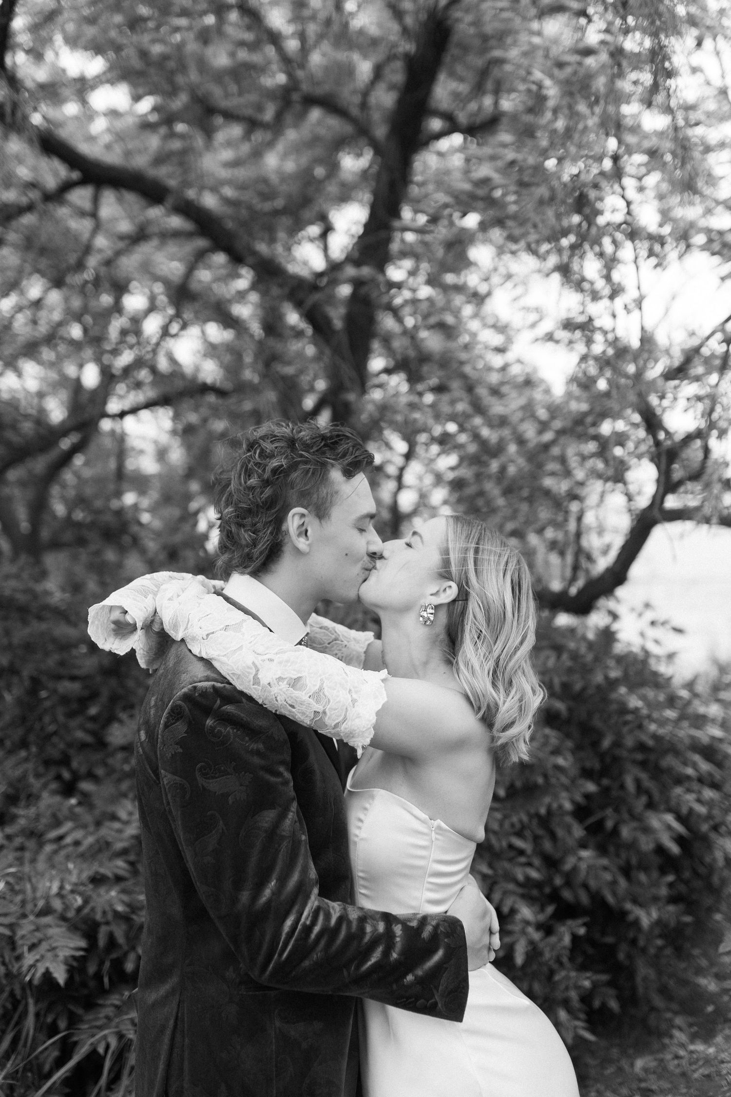 Black and white romantic wedding portrait in lush garden setting.