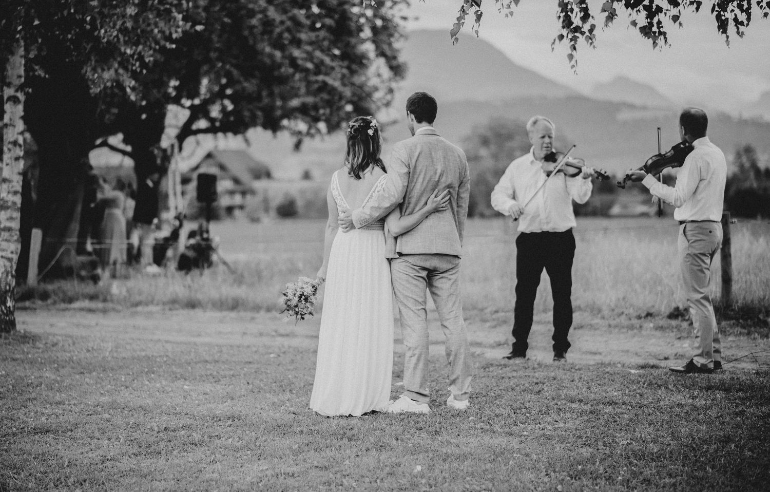 Black and white photo of a rustic outdoor wedding ceremony with mountain backdrop.