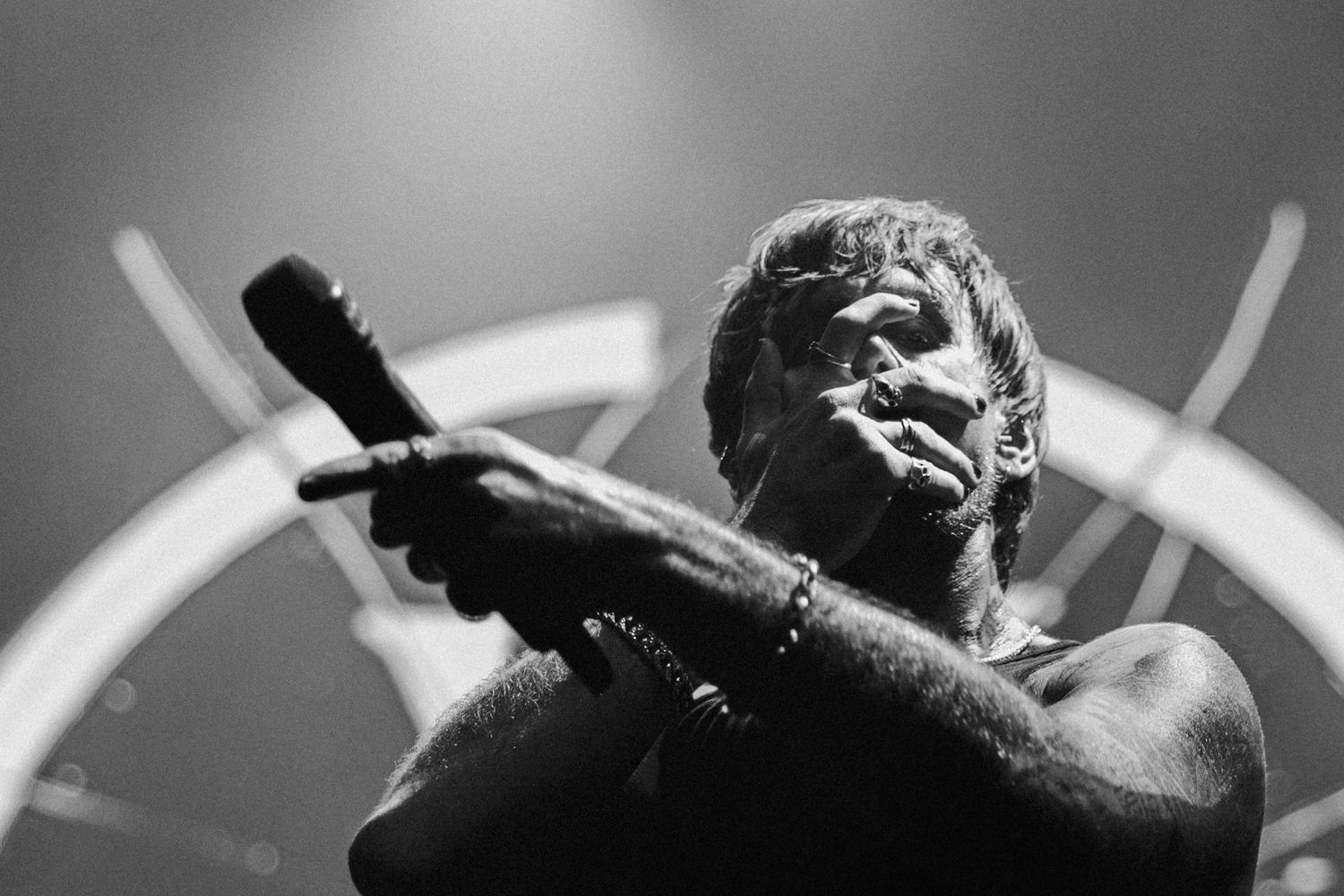 Gritty black and white close-up of a rock vocalist with a microphone. Intense monochrome music photography focusing on raw emotion.