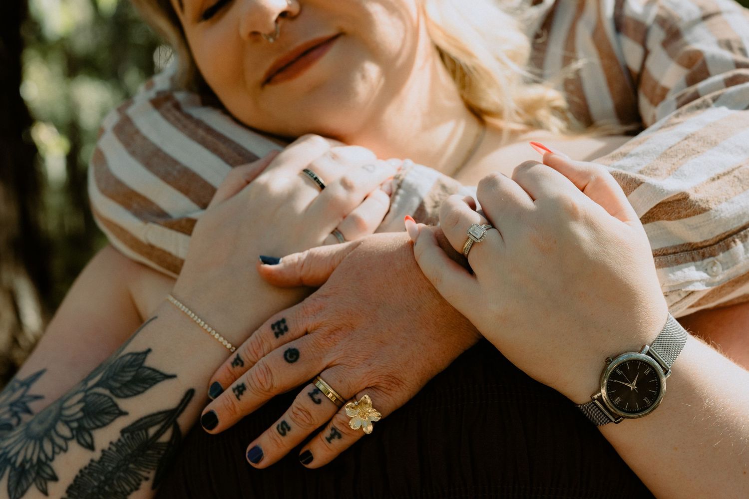 Detailed shot of a newly engaged couple's hands and engagement ring, highlighting unique tattoos and a rustic adventure aesthetic.