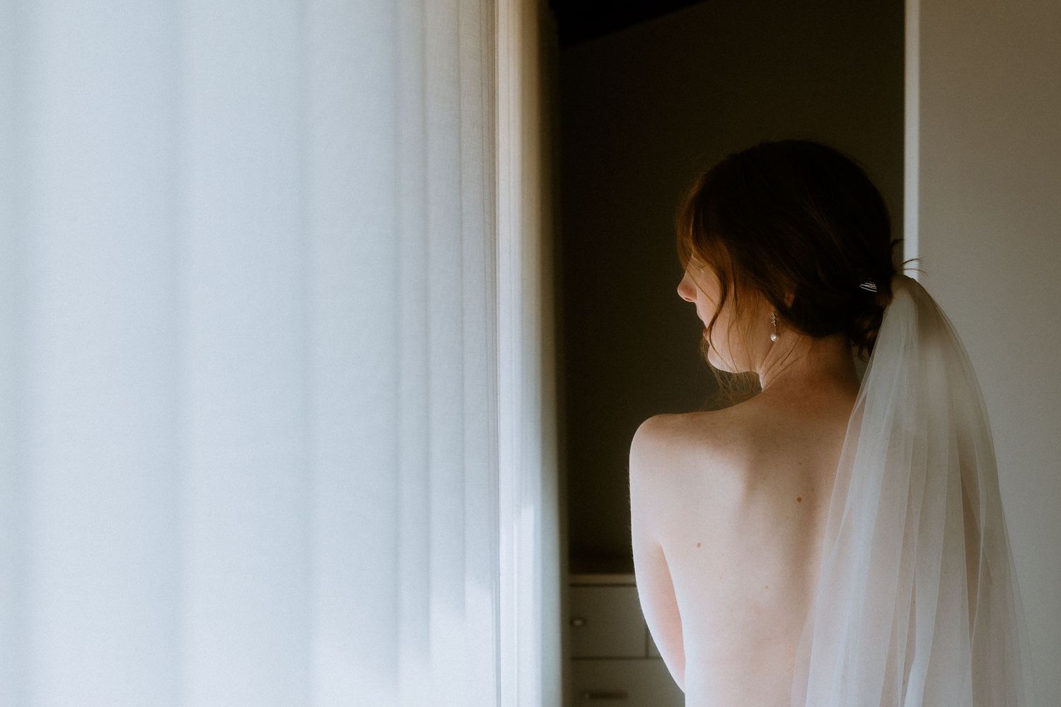Soft light bridal portrait of a woman with a low bun and wedding veil, minimalist Melbourne wedding style.