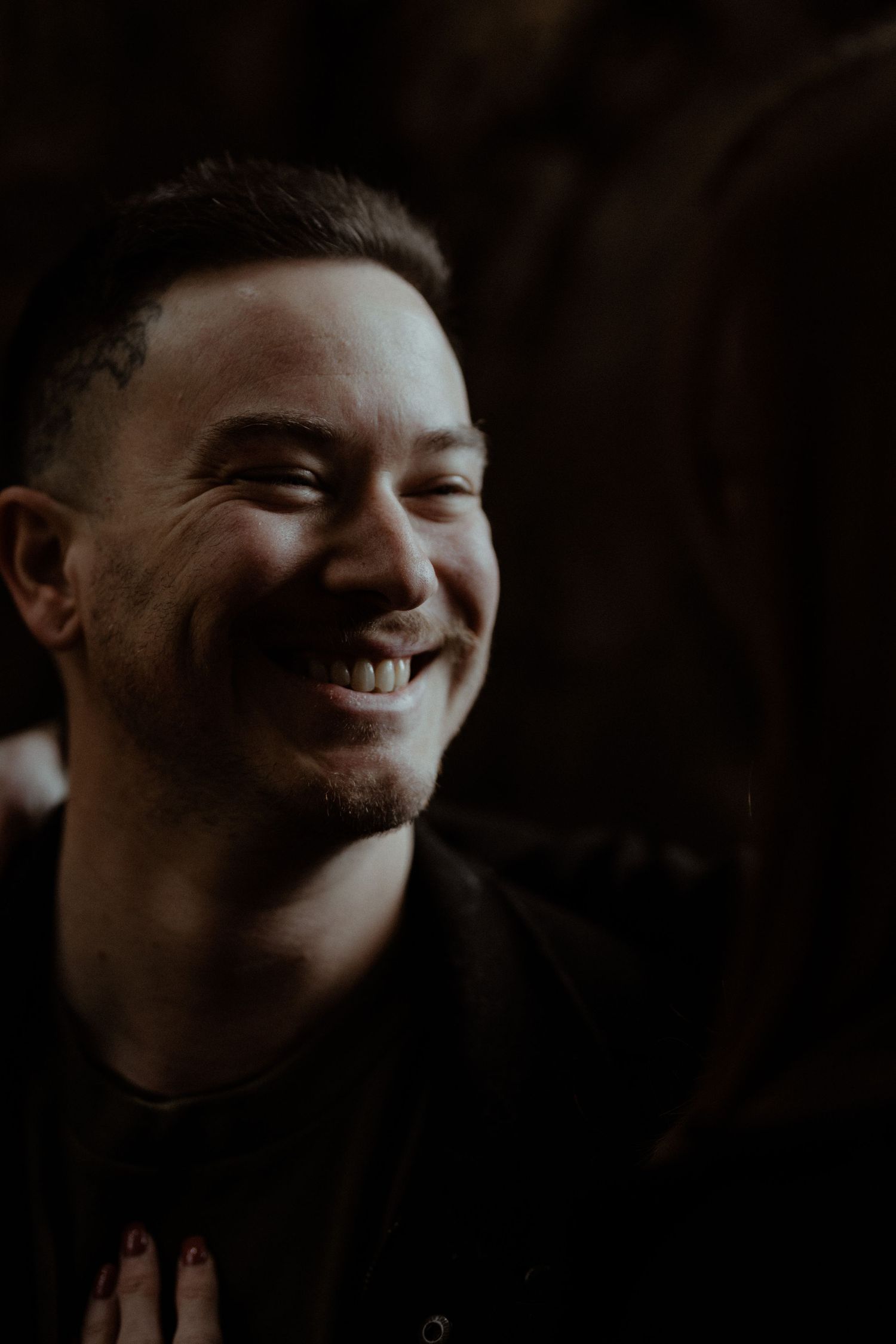Candid, moody groom portrait showing a happy, laughing man at a Melbourne wedding reception.