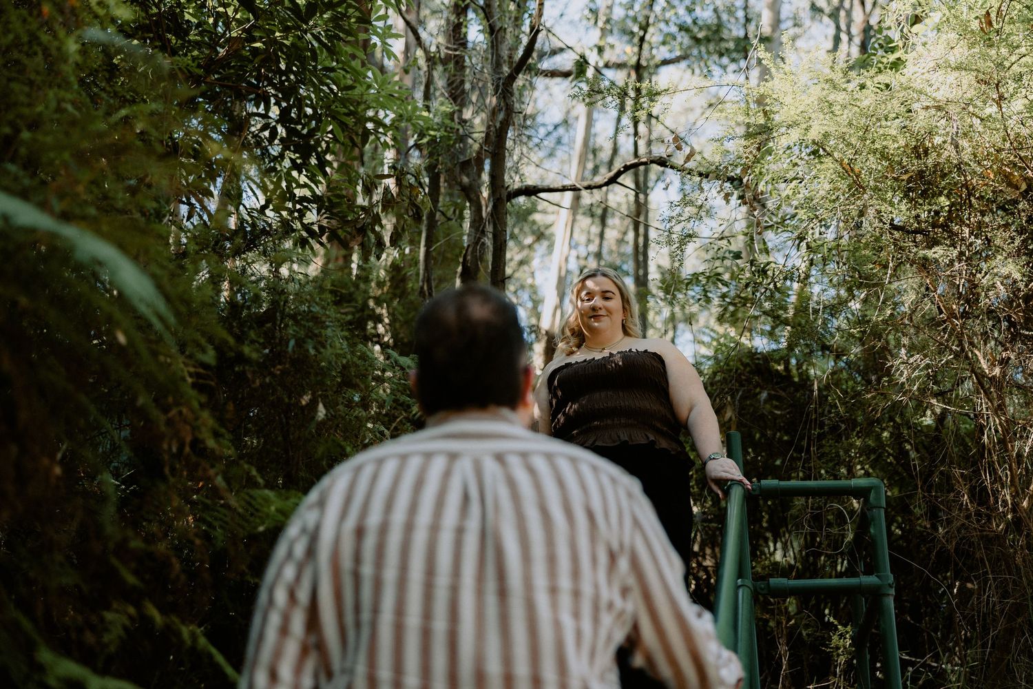Candid forest engagement photoshoot featuring a couple on a wooded trail with a rustic, natural aesthetic.