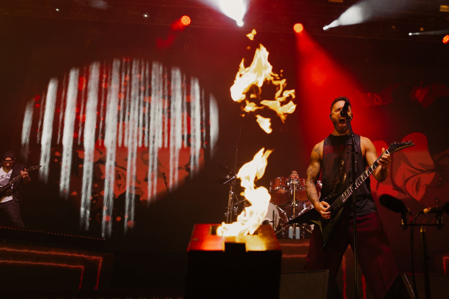 Matt Tuck of Bullet For My Valentine performing with flames. Intense heavy metal concert photography with red stage lighting.