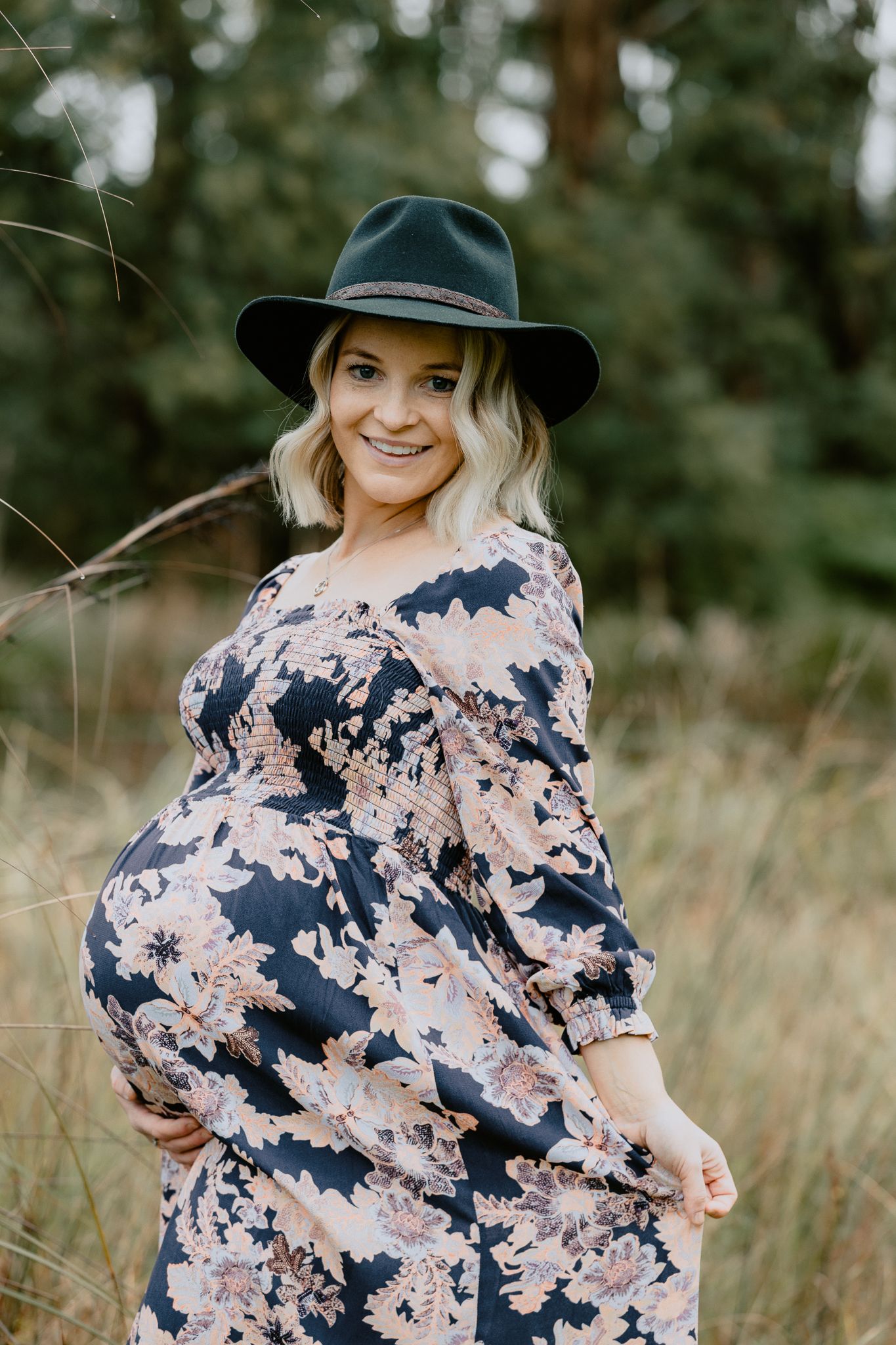 Outdoor maternity photography session in eastern suburbs of Melbourne featuring a pregnant woman in a floral dress and black felt hat.